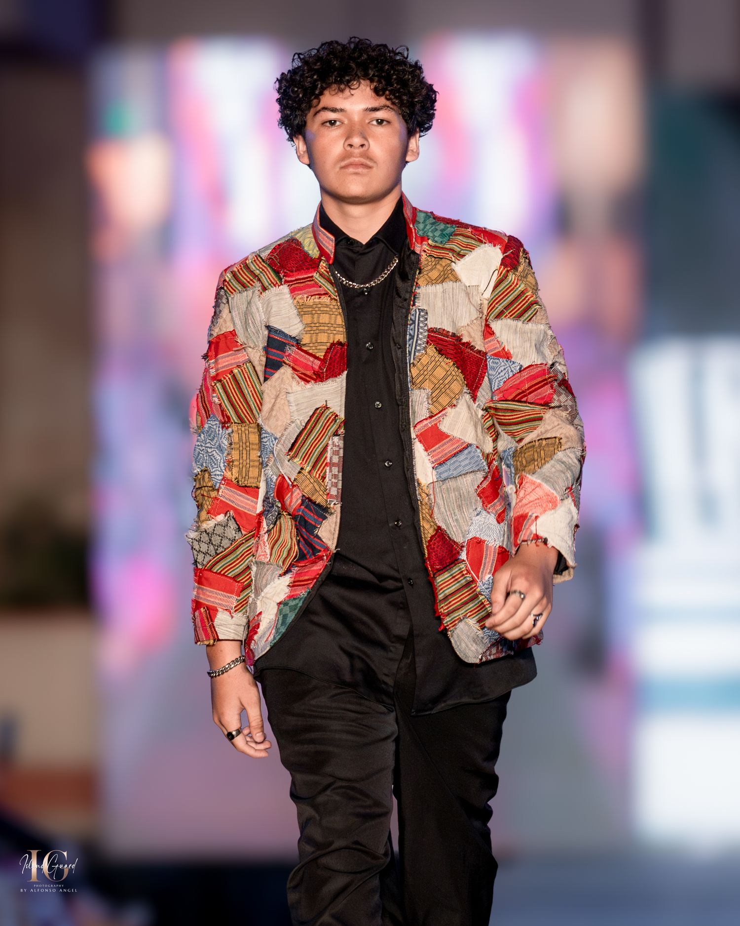 Stylish patchwork-patterned blazer paired with black pants on fashion runway.