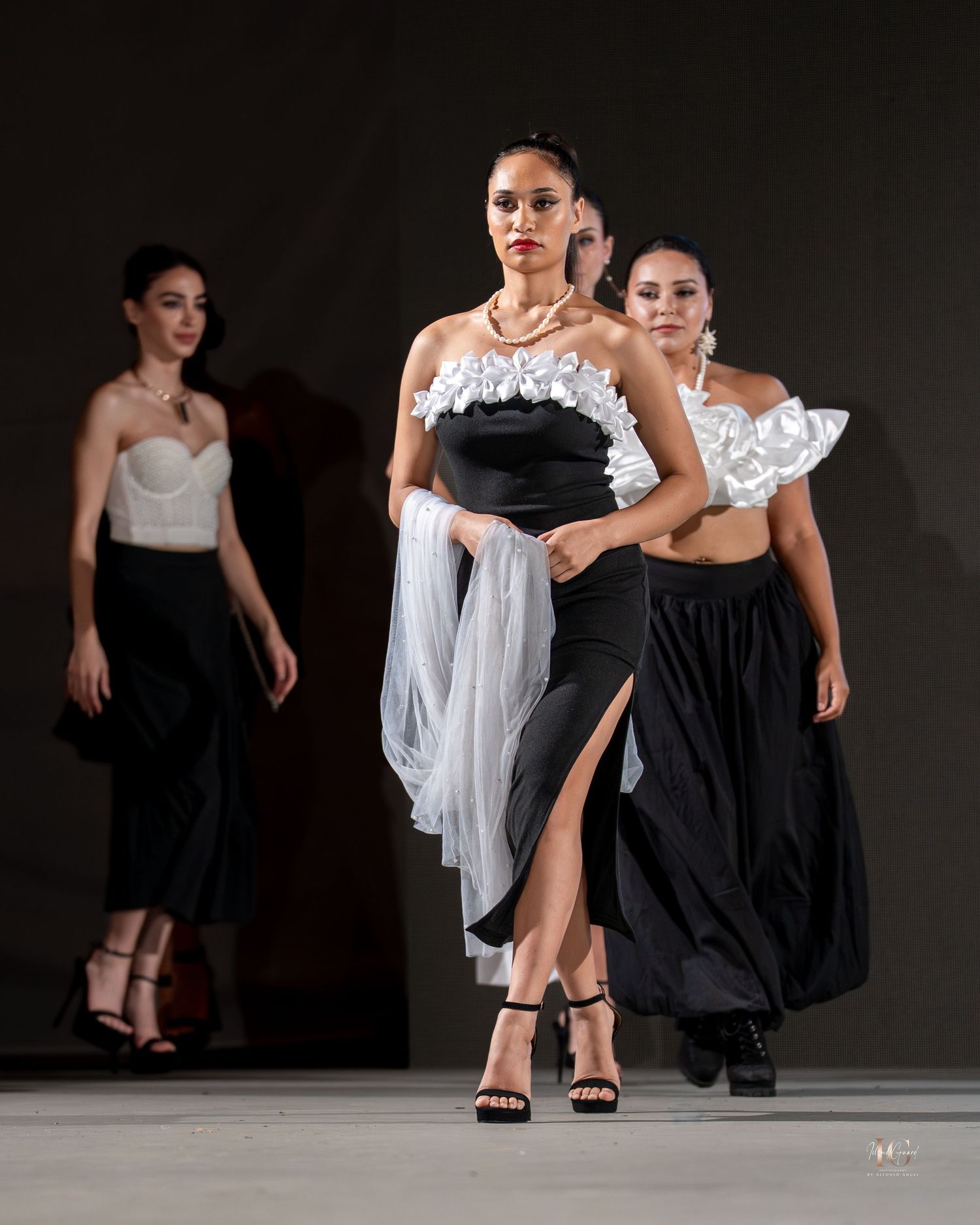 Dancers in black and white costumes perform a contemporary dance sequence on a dark stage.