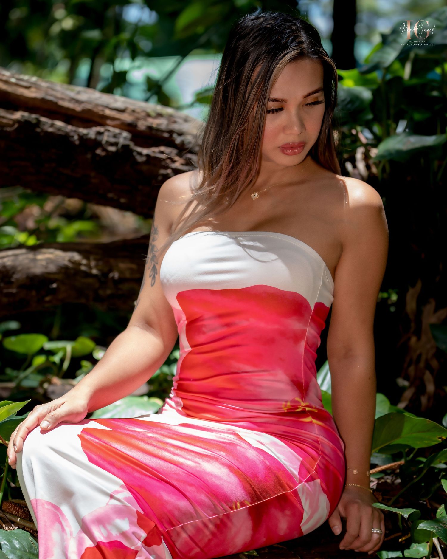 A person in a strapless white and coral pink dress poses outdoors against a natural backdrop with foliage.