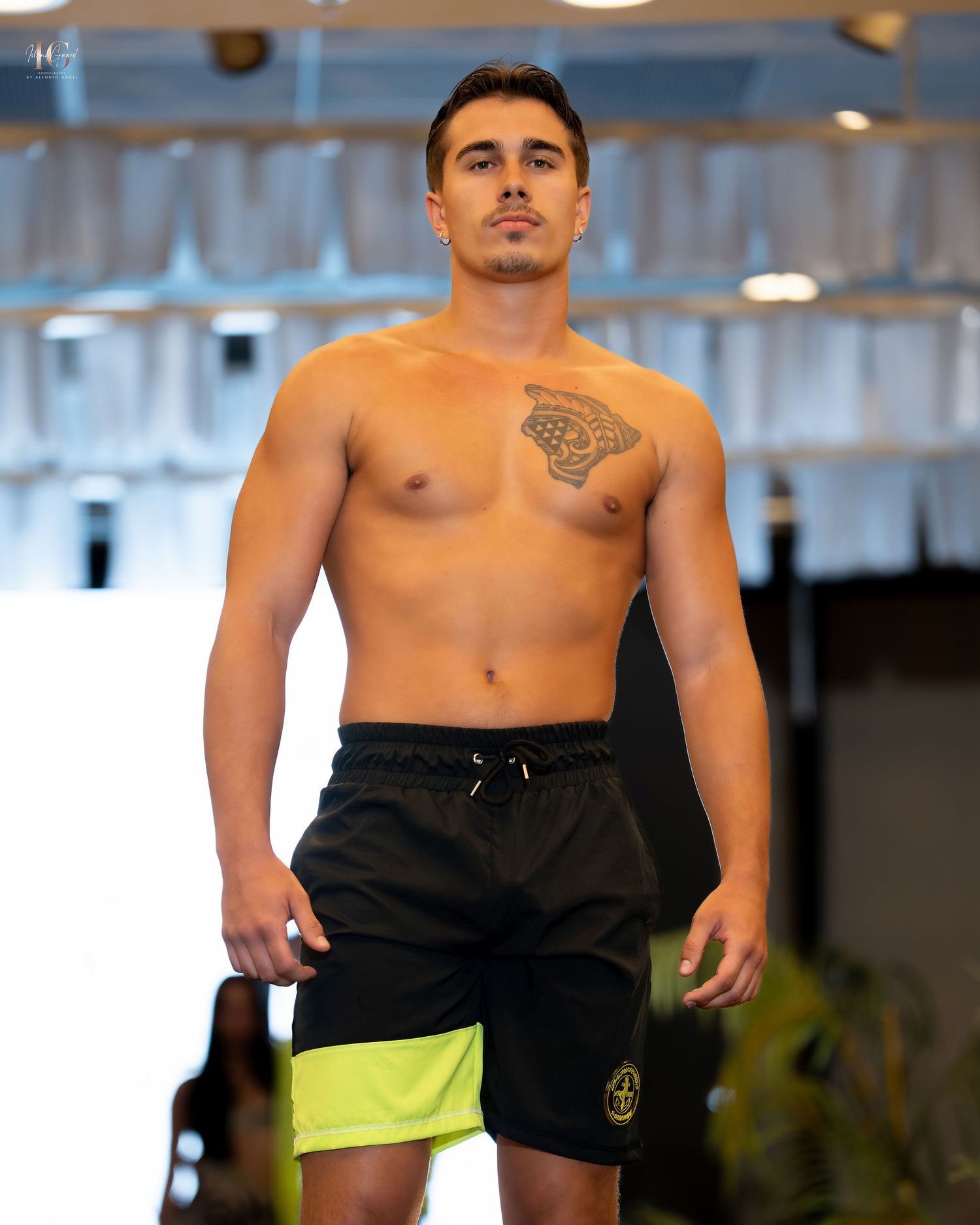 Athletic person wearing black and yellow swim shorts demonstrates active poses during beachwear fashion shoot.