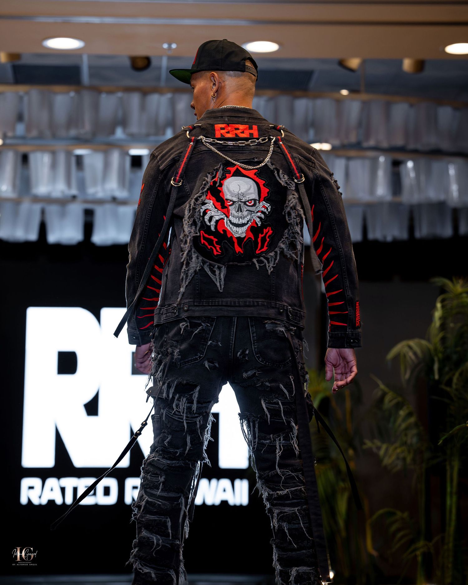 A black leather jacket with red accents and a skull design on the back displayed in different angles.