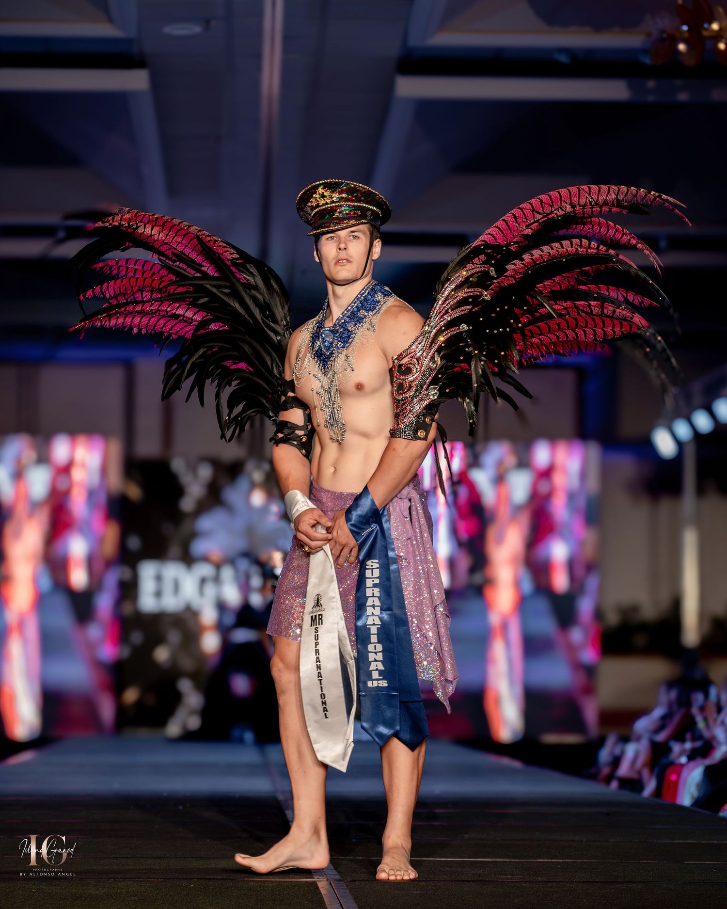 Dramatic runway look with red feather wings and nautical-inspired costume elements.