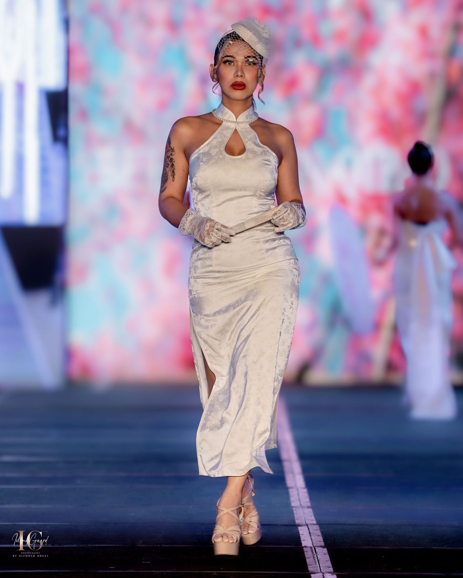 Cream colored evening wear collection featuring minimalist design on illuminated catwalk.
