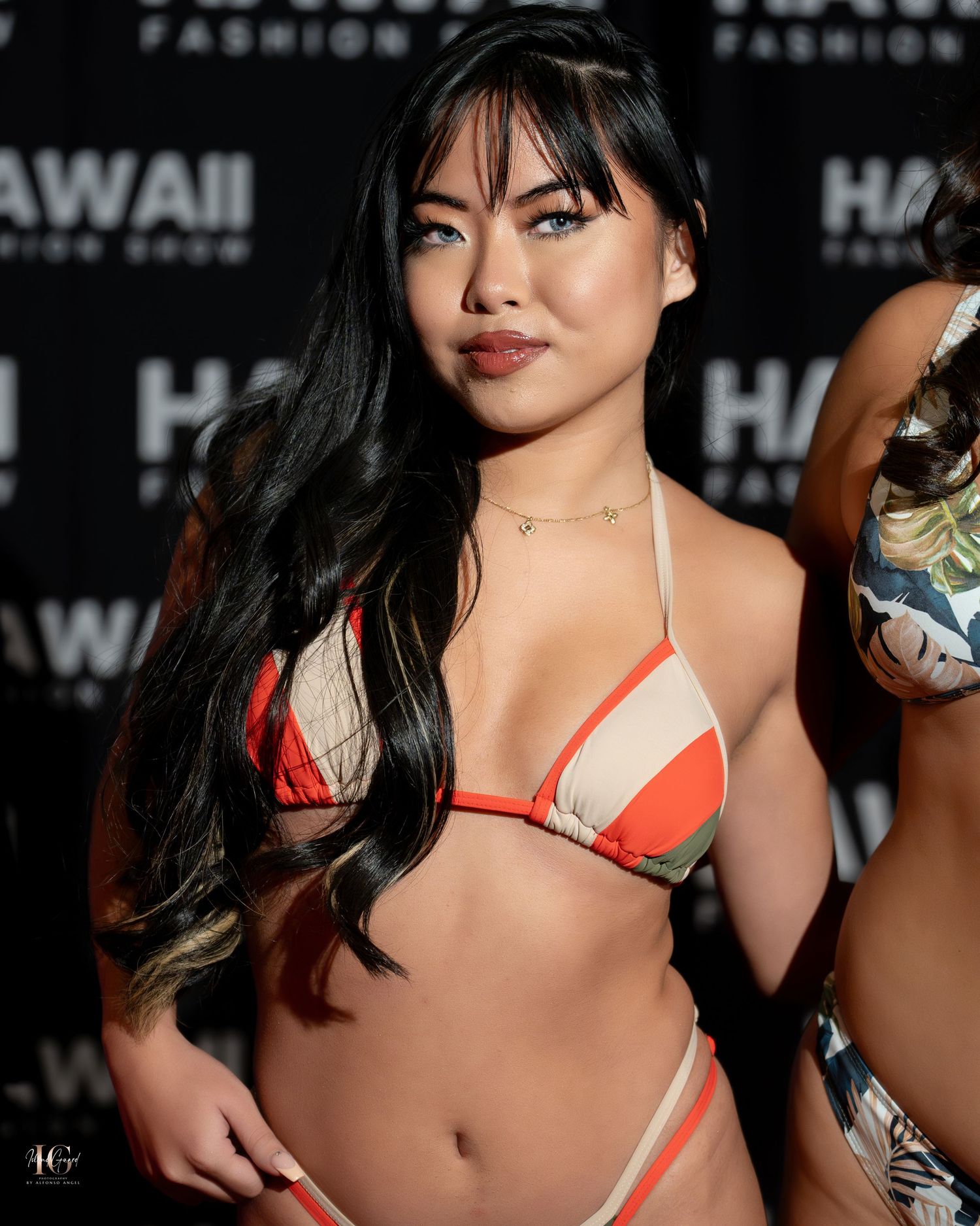 Fashion model in orange and white striped bikini poses at Hawaii fashion event.