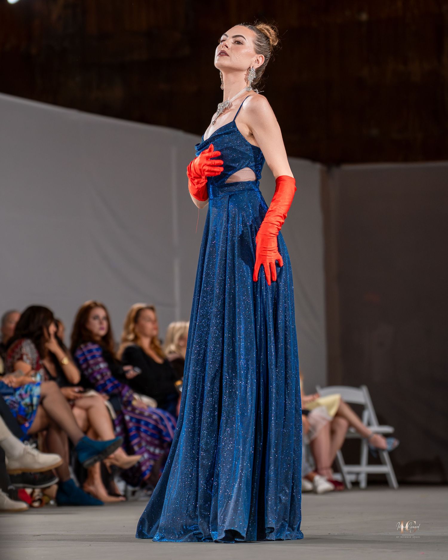 A performer in a sparkly blue evening gown and red gloves strikes dramatic poses during a stage performance.