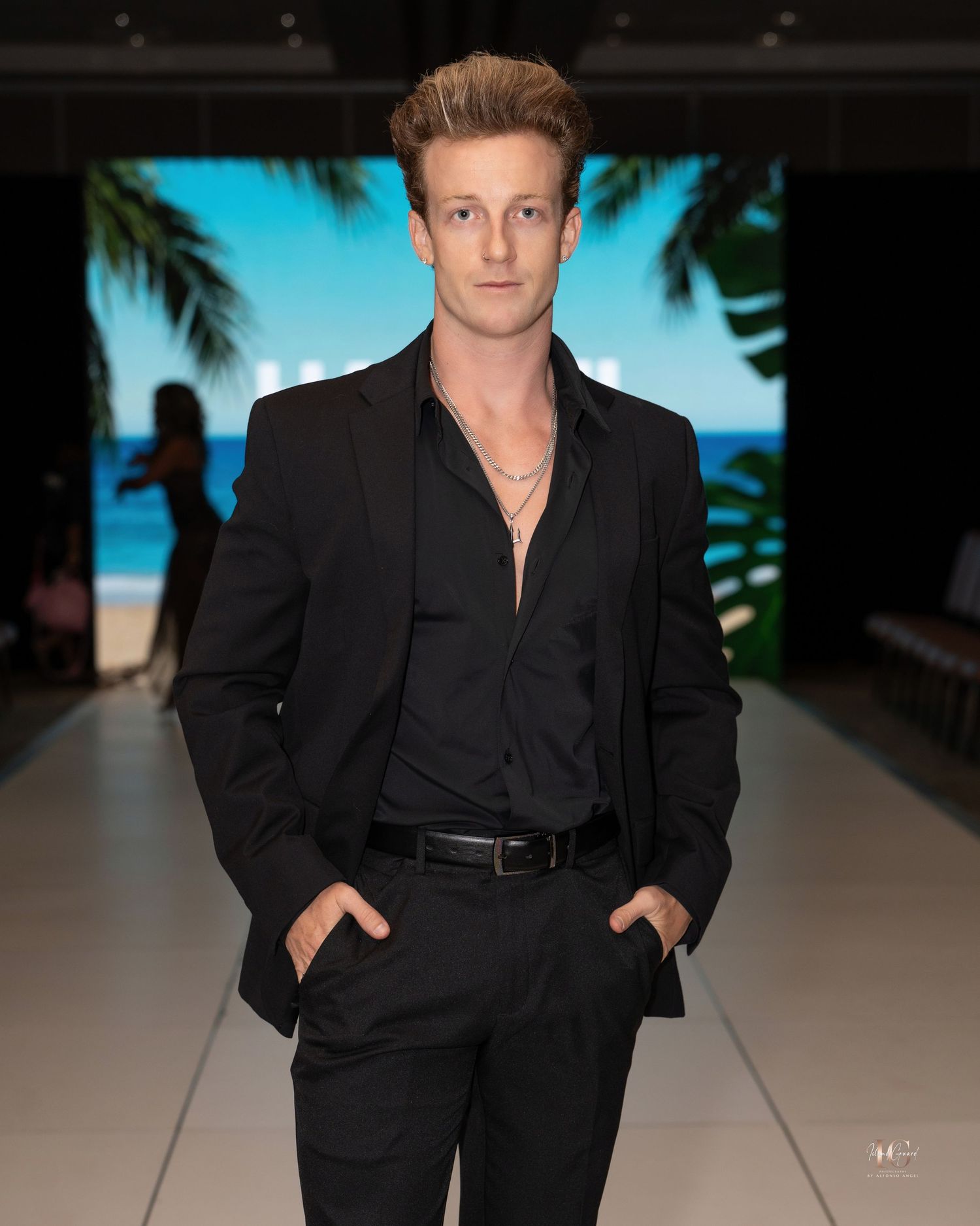 A model walks the runway wearing an all-black suit with a plunging neckline during a fashion show.