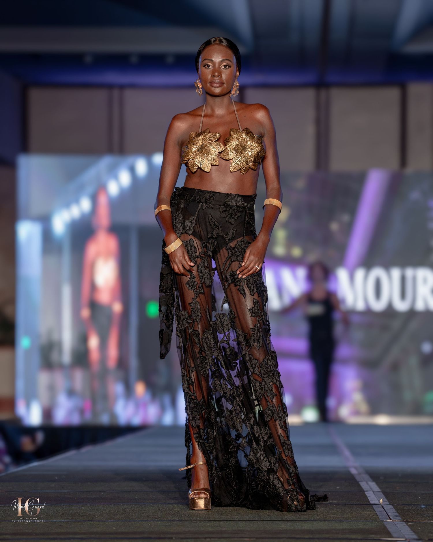 Gold metallic crop top paired with sheer black skirt showcased at evening fashion show.