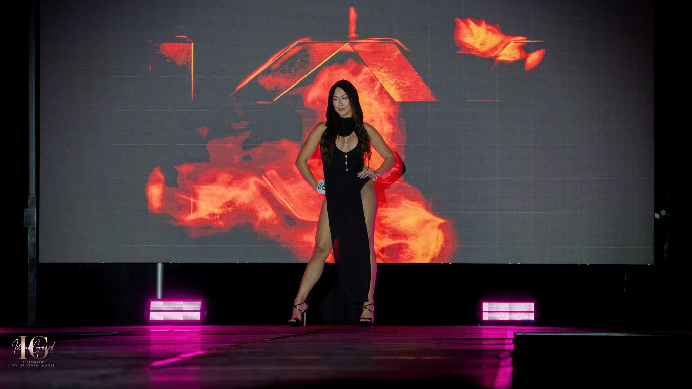 Fashion model walks runway against dramatic red digital backdrop with stylized flame effects.