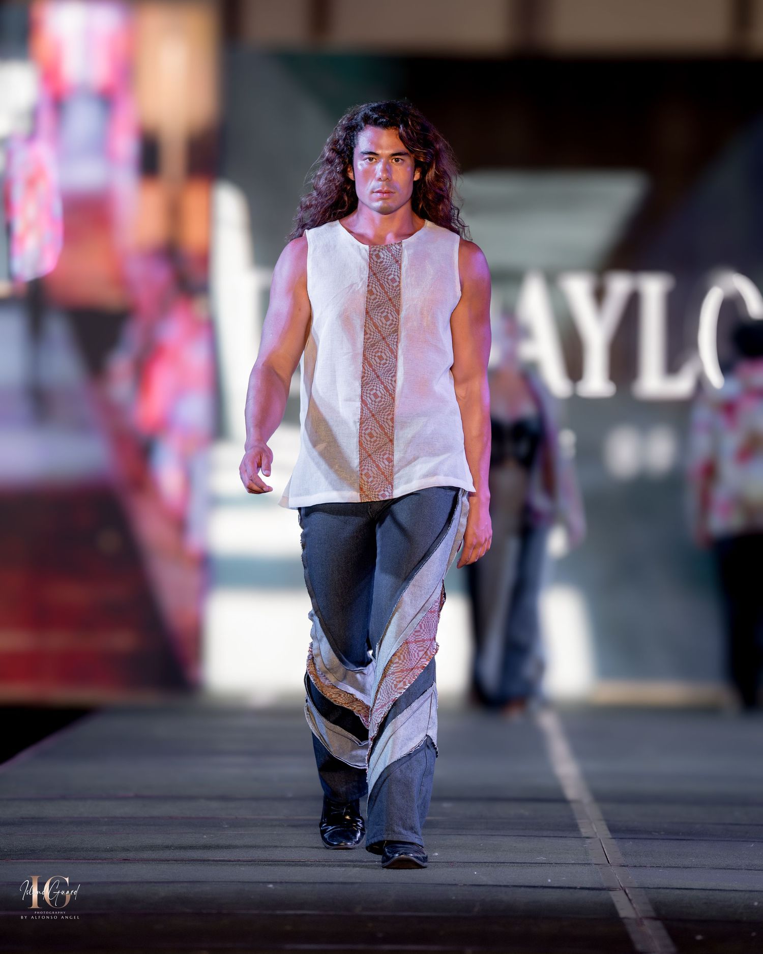 White sleeveless top with geometric pattern detail paired with two-tone pants on runway.