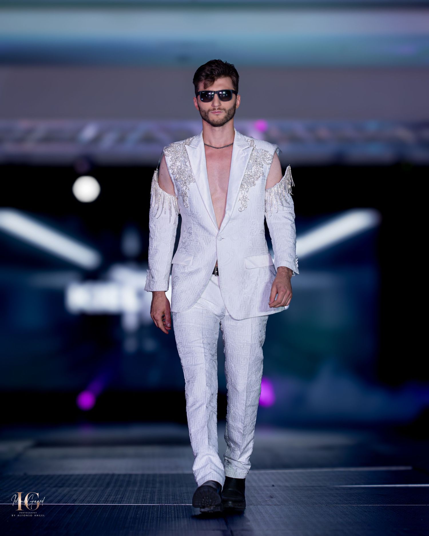 Model presents crisp white tailored suit with structured shoulders on fashion runway.