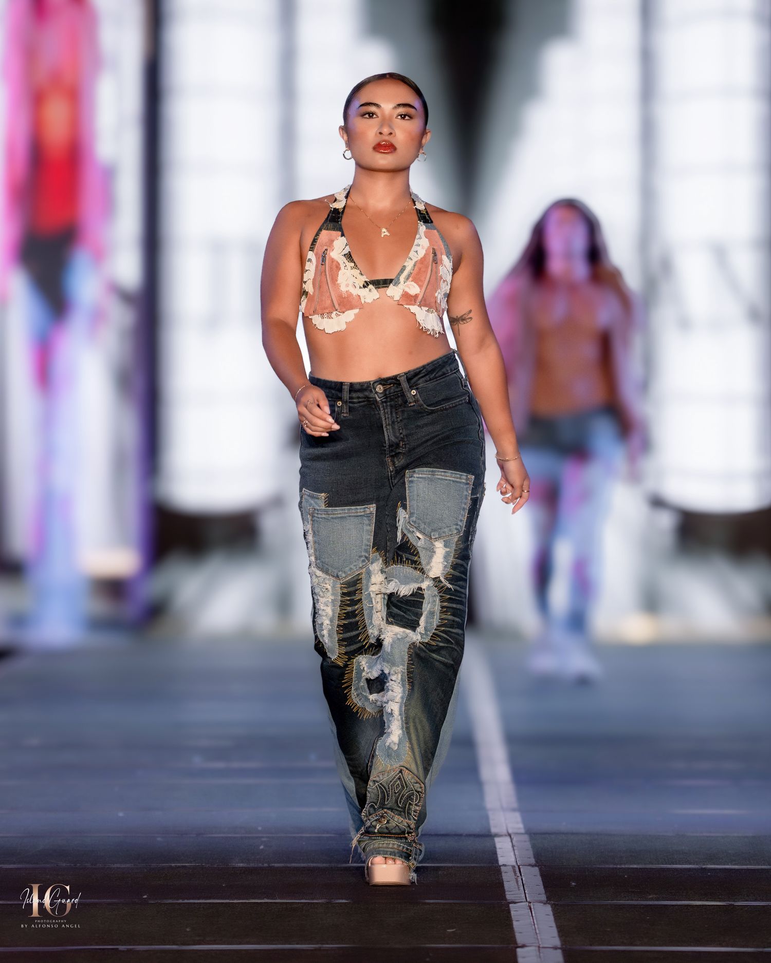 Model walks runway in heavily distressed denim jeans with artistic patchwork details.