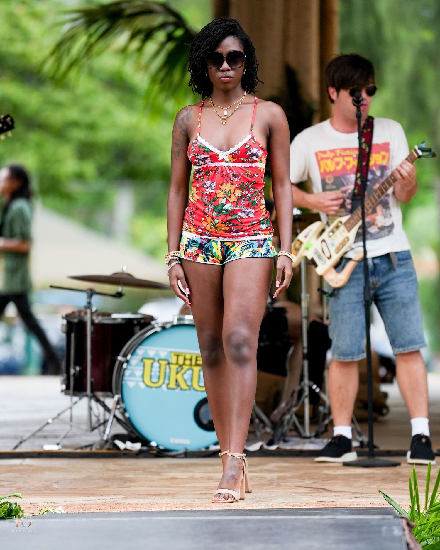 People in colorful swimwear enjoying a summer pool party with a live band performing in the background.
