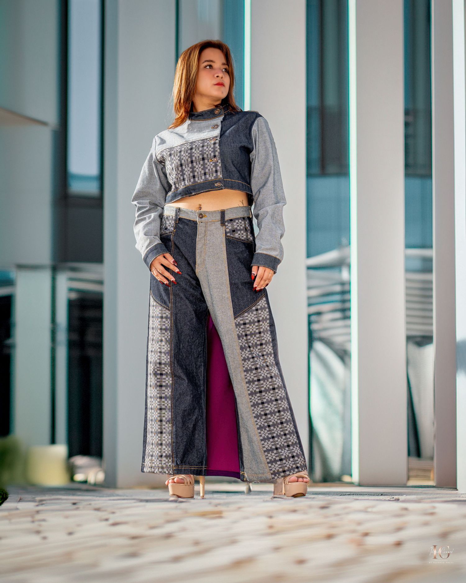 Fashion model wearing grey patterned coat posing in modern architectural setting.