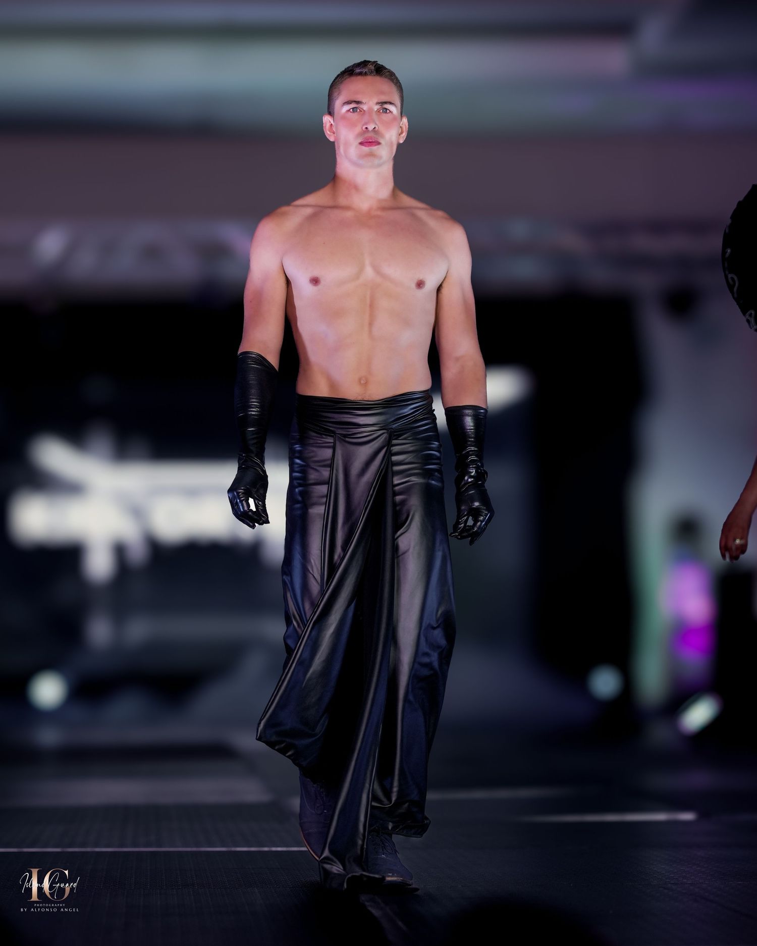 Minimalist black pants with leather gloves on fashion runway.