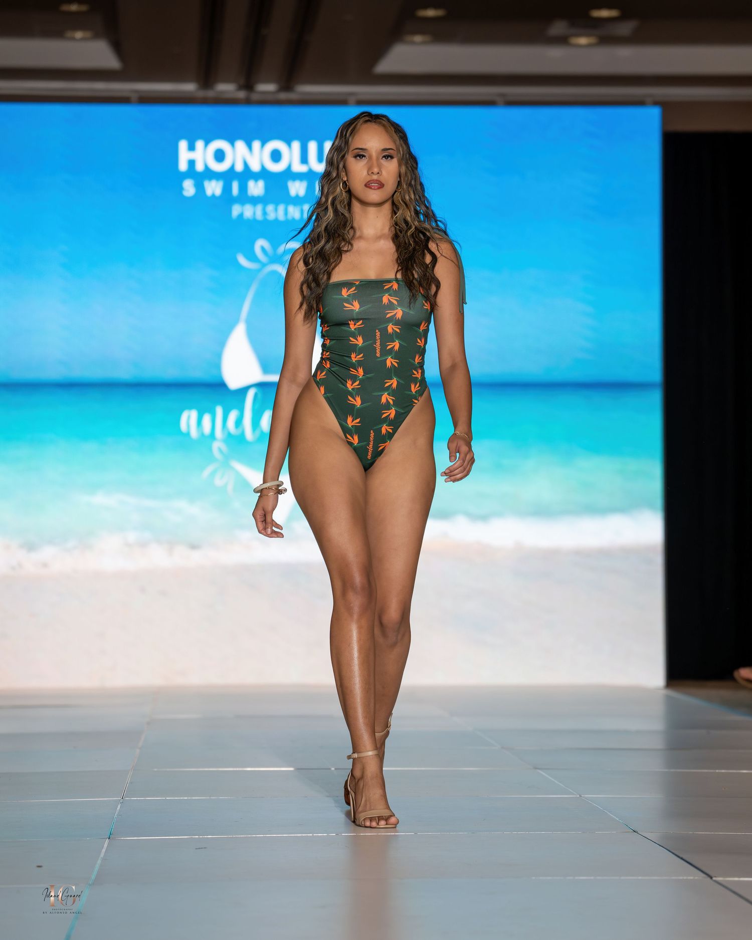Tropical print swimwear collection showcased on beachwear runway with beach background.