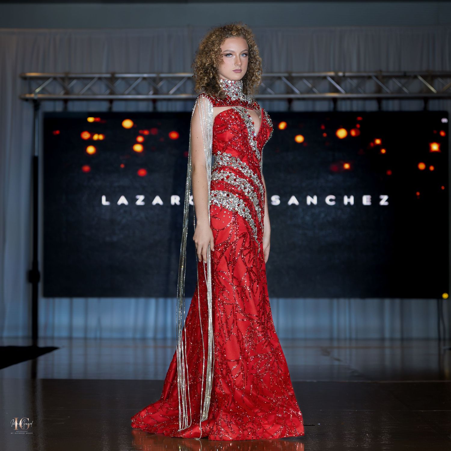 Full-length red sequined gown with silver beading and side slit on fashion runway.
