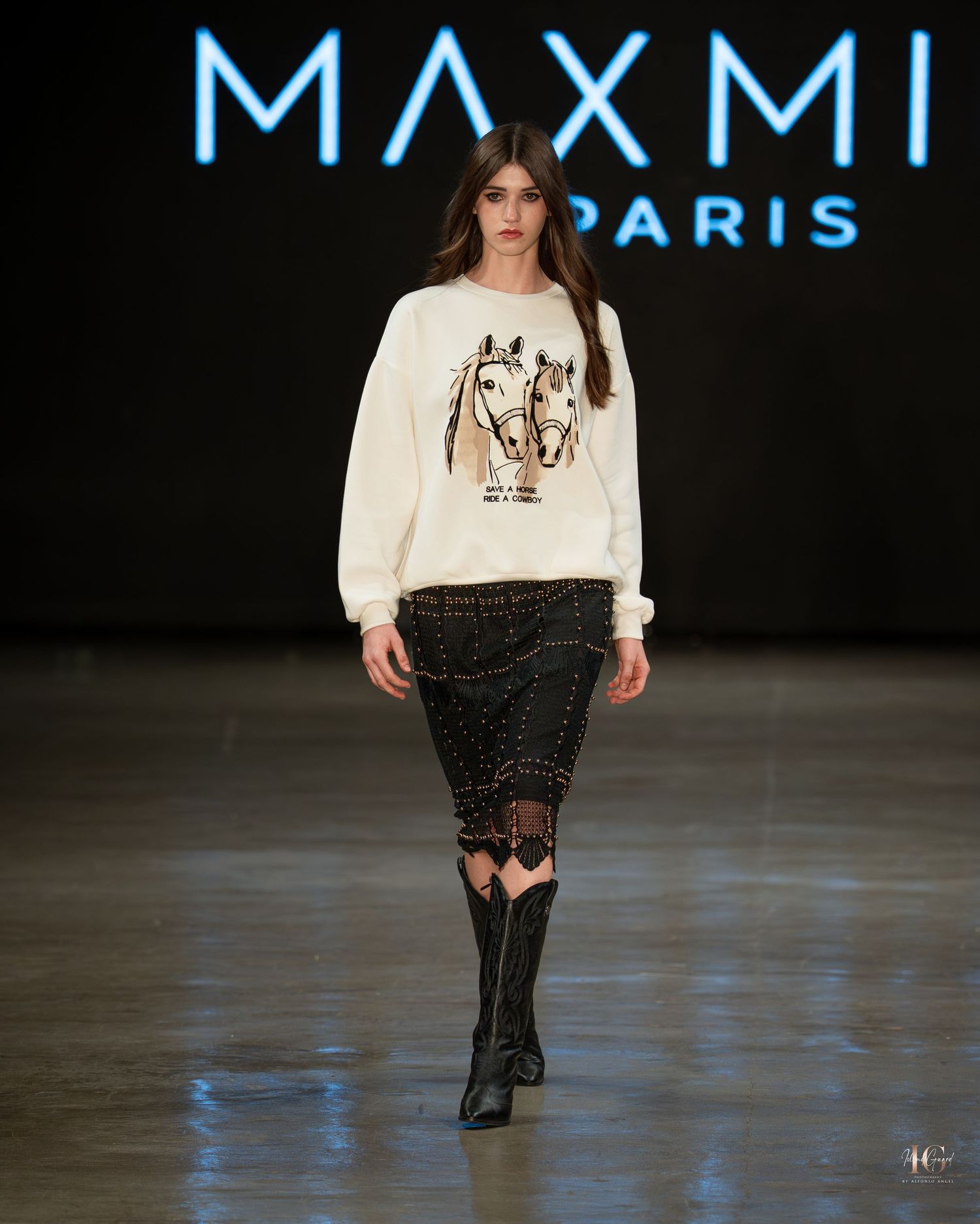 Fashion model walks runway in cream sweater and black studded skirt during MAXMI Paris fashion show.
