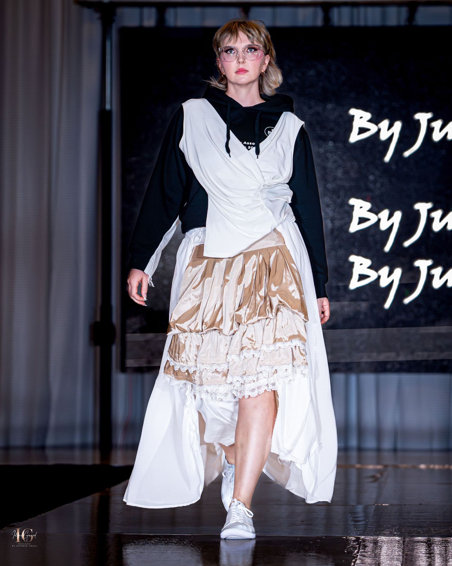 Model showcases avant-garde white layered dress with beige details on runway.