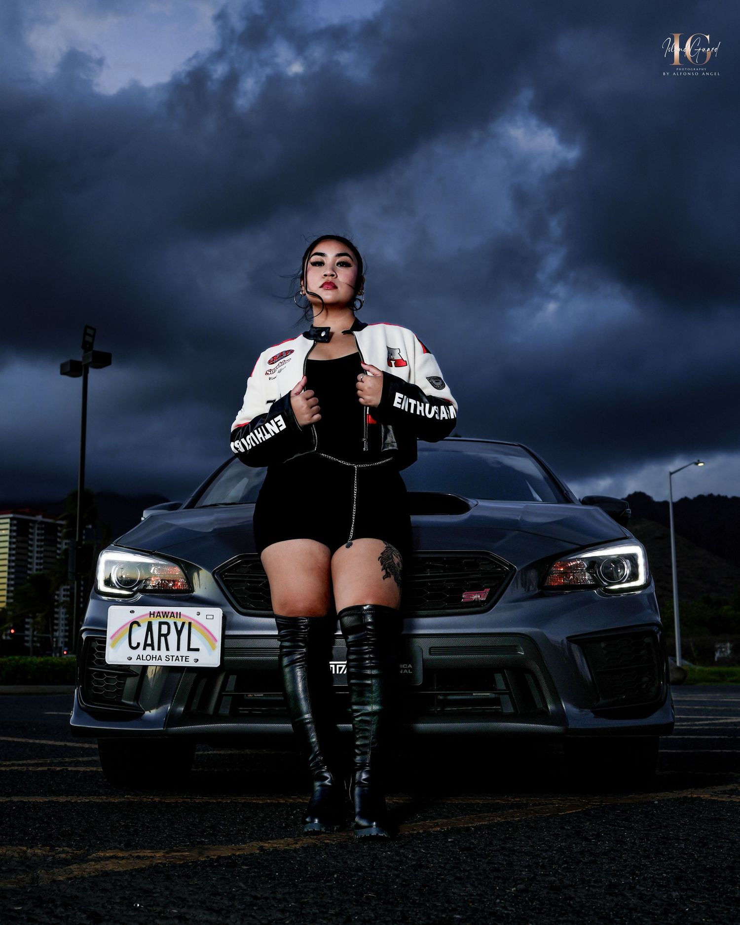 A figure poses in front of a Subaru WRX at night with dramatic stormy clouds overhead.