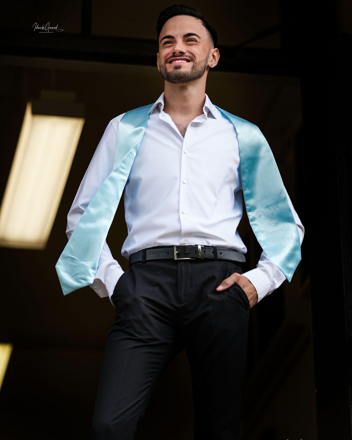 A person in a white dress shirt and light blue suit jacket stands confidently in dramatic lighting.