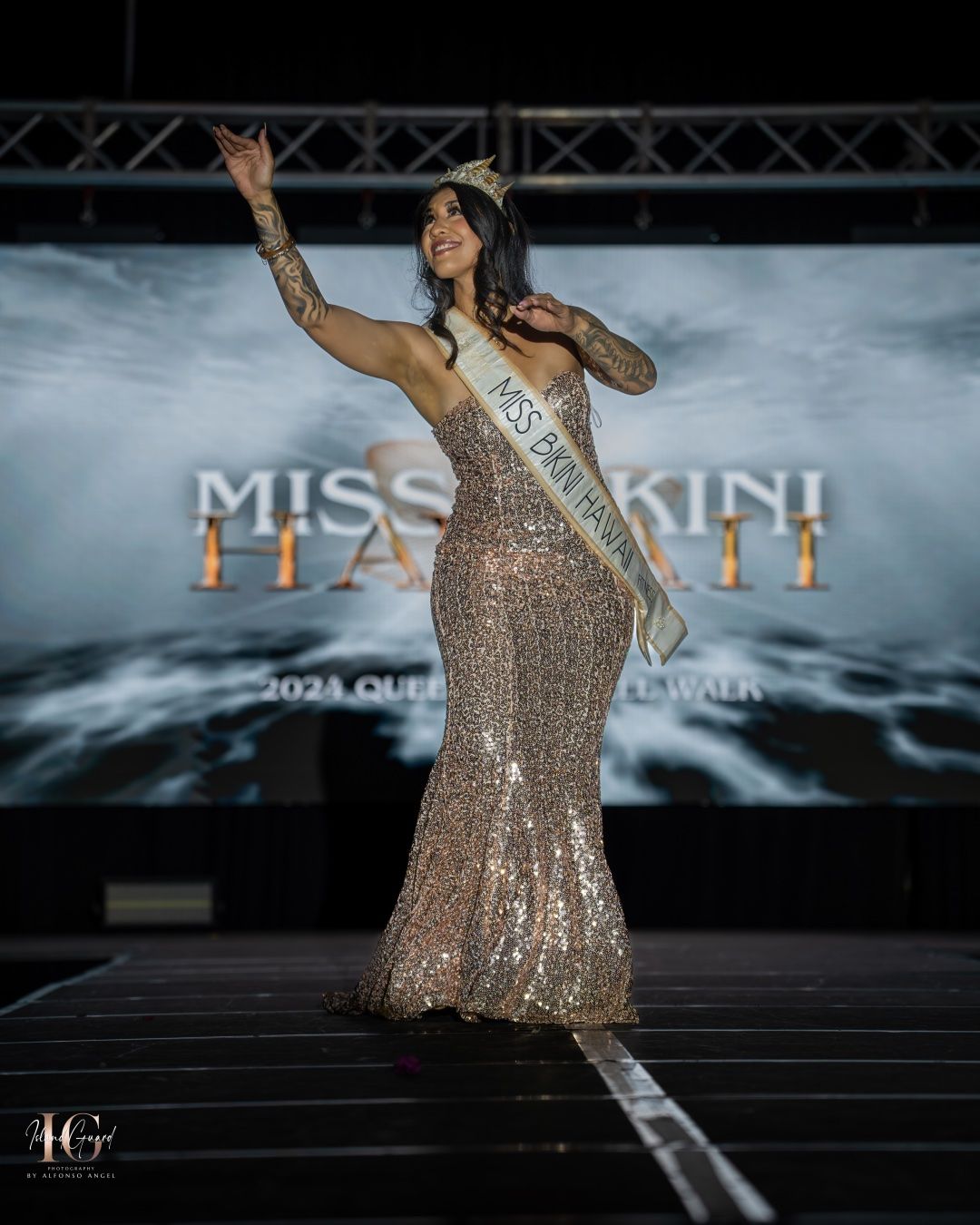 A contestant in a sparkly gold evening gown performs on stage at the Miss Bikini pageant competition.