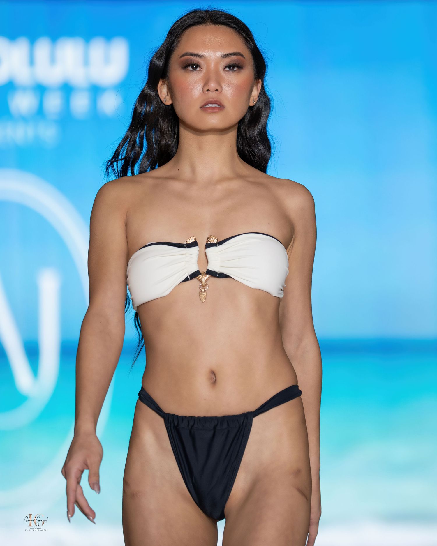 Models present white and black contrast swimwear collection on catwalk.