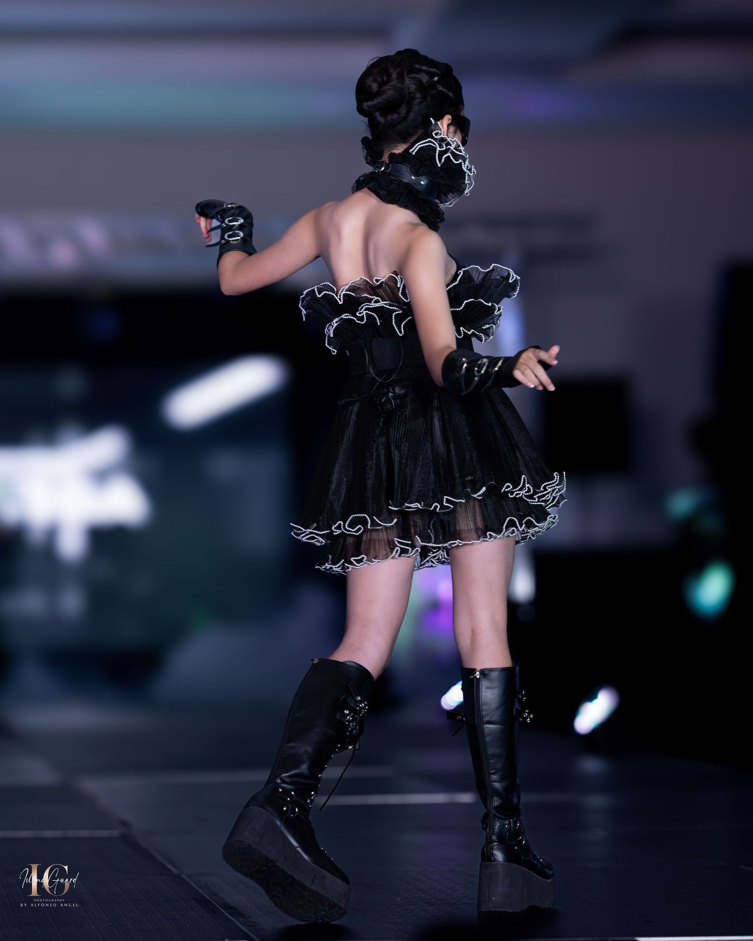 Fashion show features dramatic black tulle dress with contrasting white trim and platform boots.