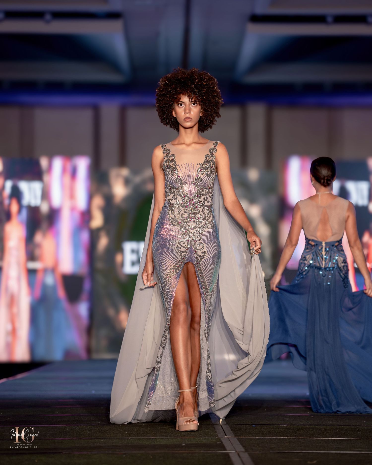 Ethereal silver-grey evening gown with cape details and intricate beadwork on fashion catwalk.