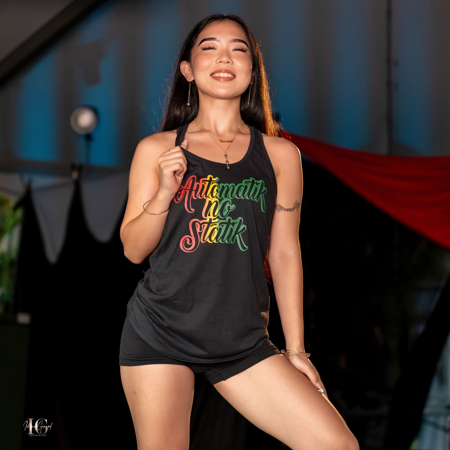 Models showcase graphic print tank tops on dark fashion runway.