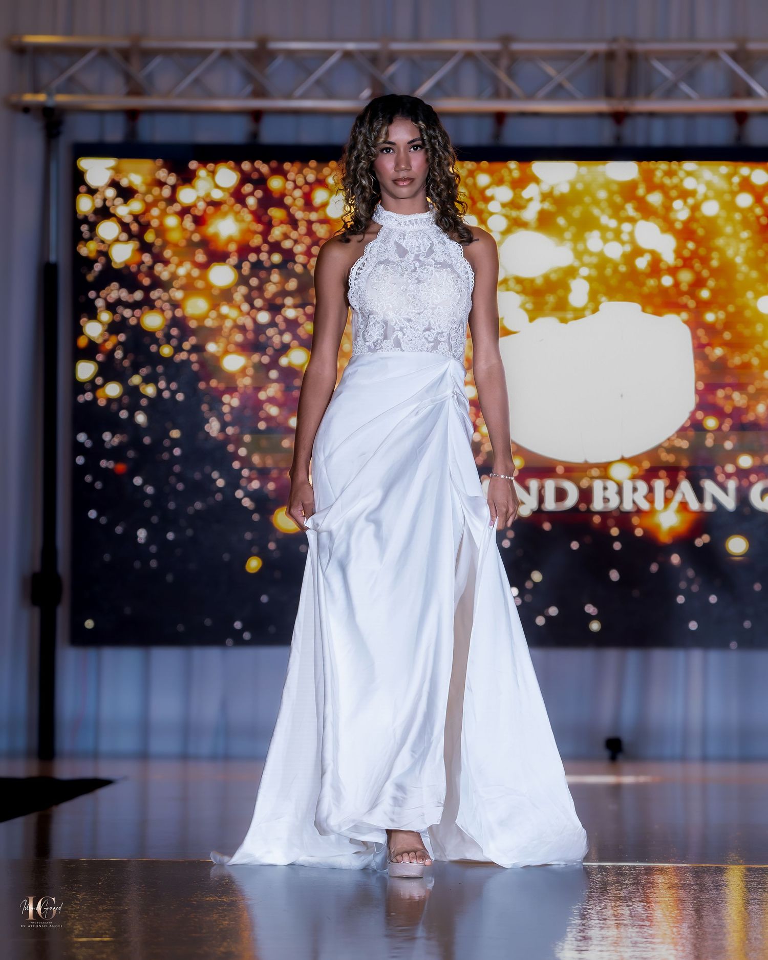 Bridal collection featuring white floor-length gowns presented on illuminated catwalk.