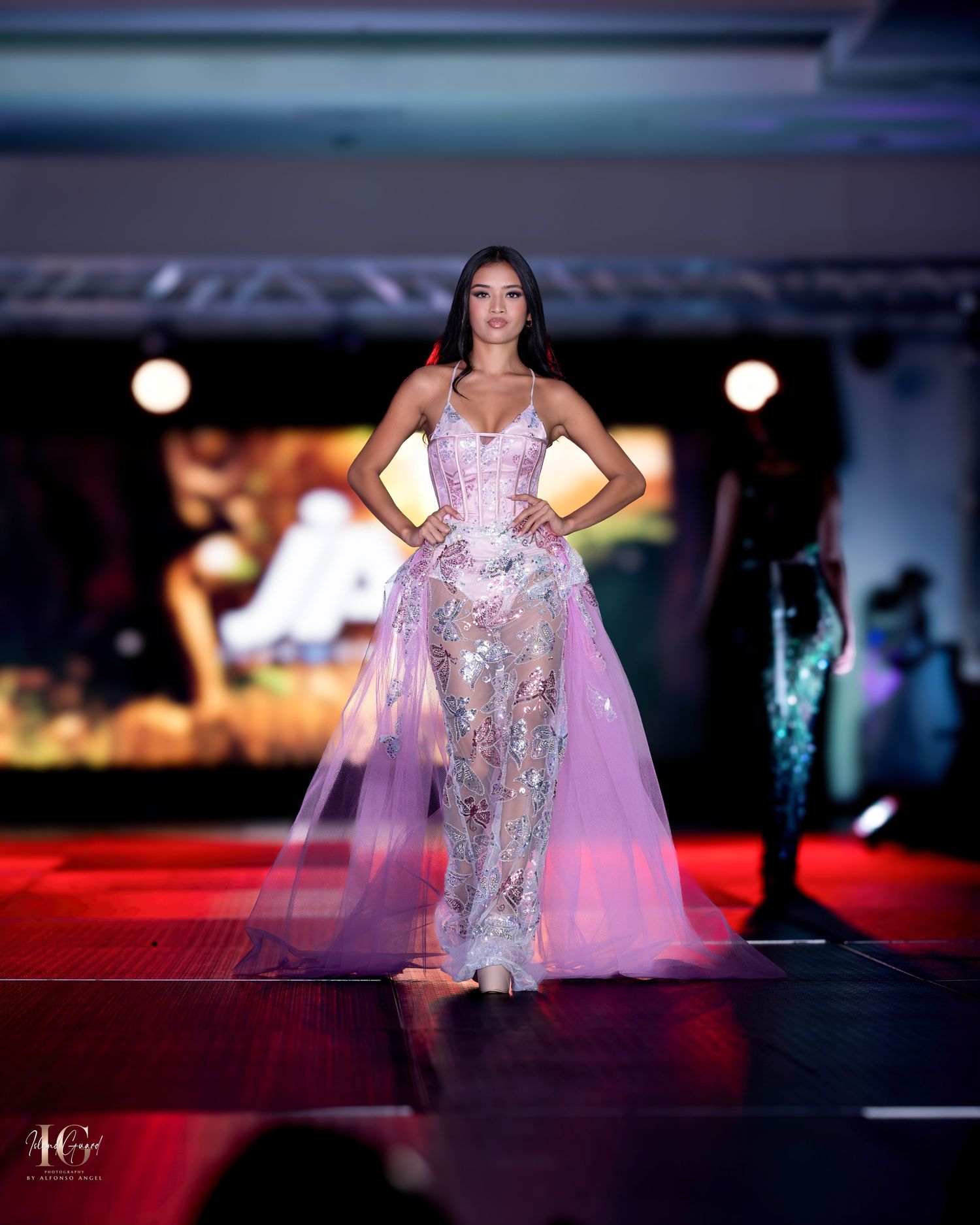 Sparkling silver evening gown with flowing pink cape creates dramatic silhouette on fashion runway.