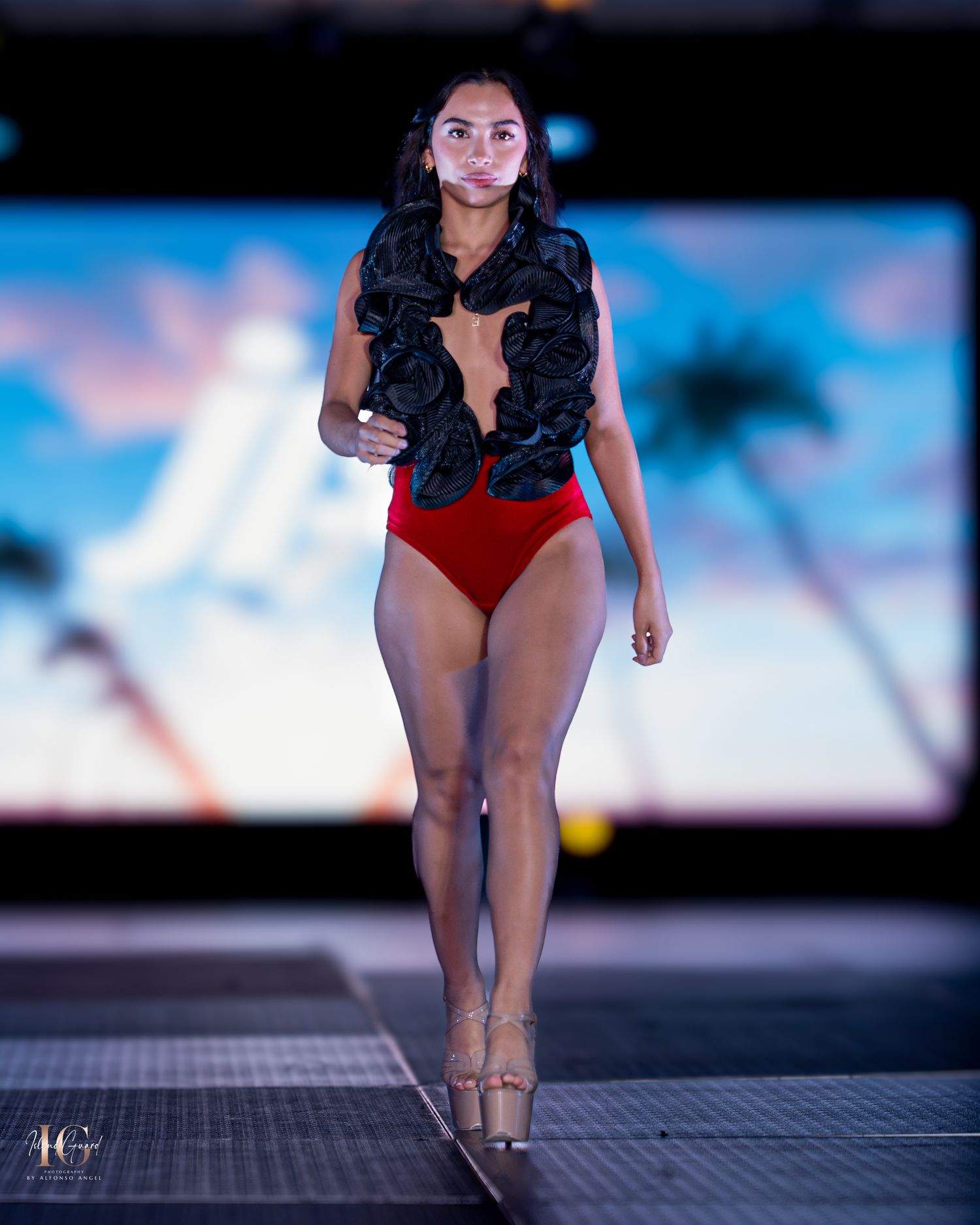 Red swimsuit collection showcased on runway with blue gradient lighting effects.