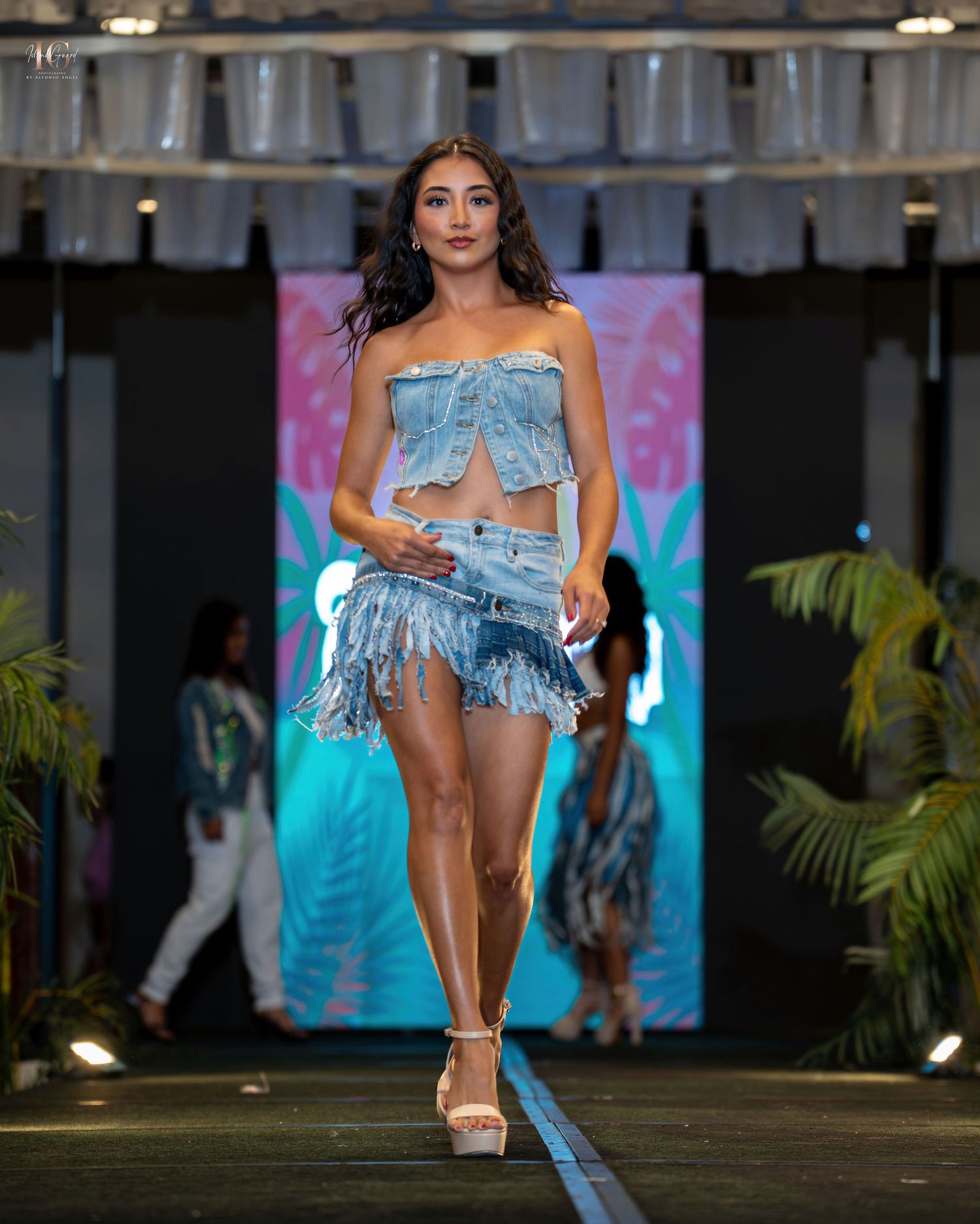 Models walk the runway in light blue denim swimwear and resort wear during a summer fashion show.