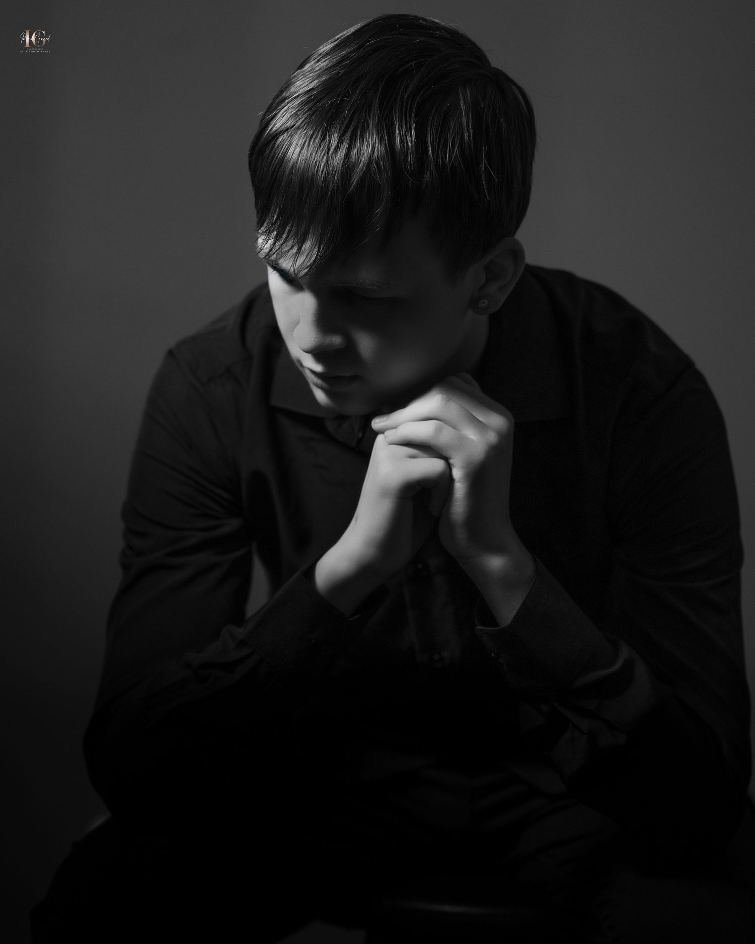 Moody black and white portrait showing figure in contemplative pose.
