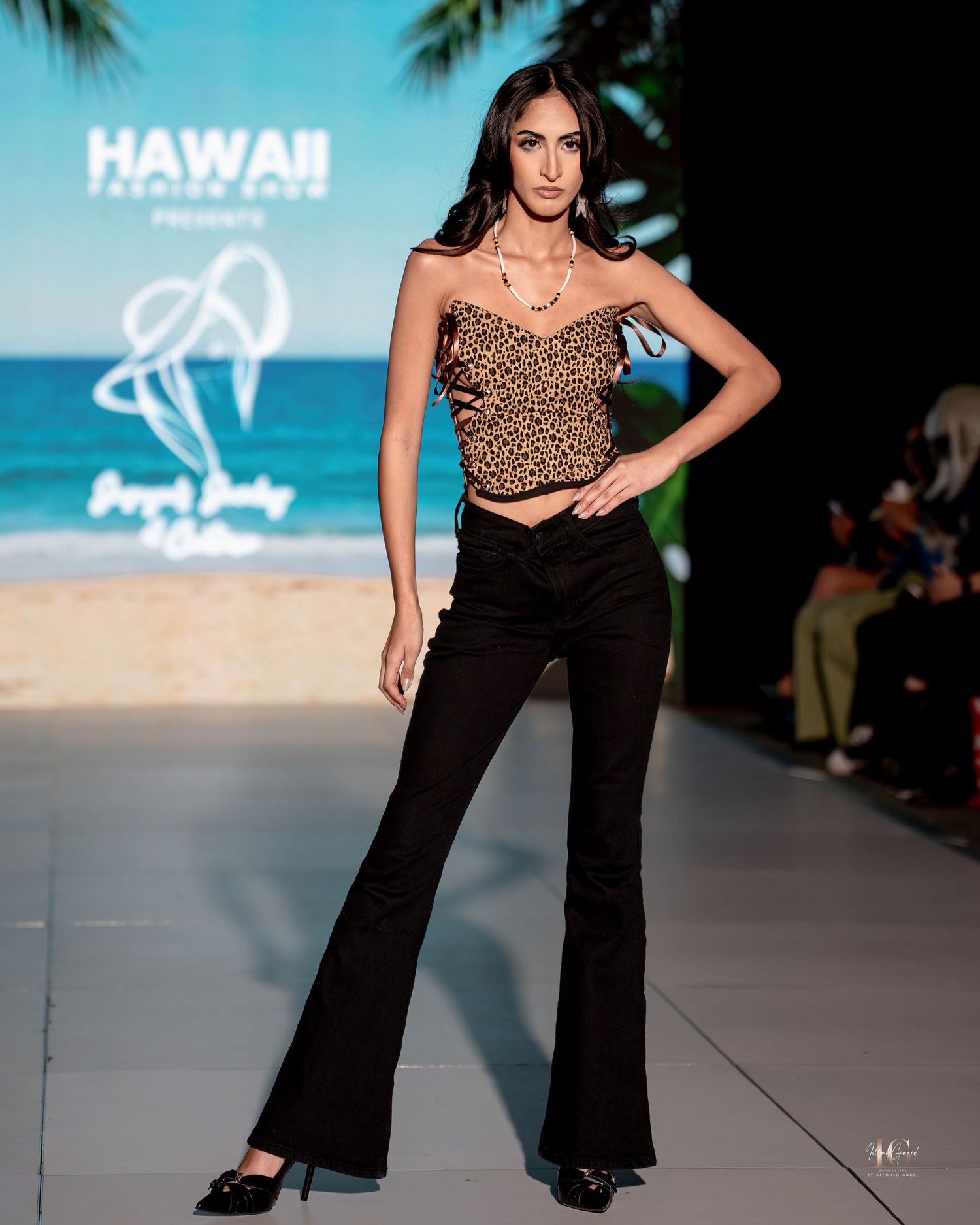 Model walks runway in leopard print crop top and black flared pants during Hawaii fashion show.