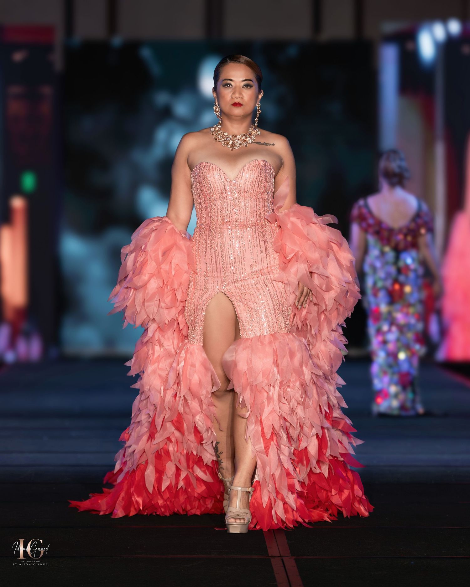 Coral feathered high-low gown with structured bodice and dramatic ruffles on fashion runway.