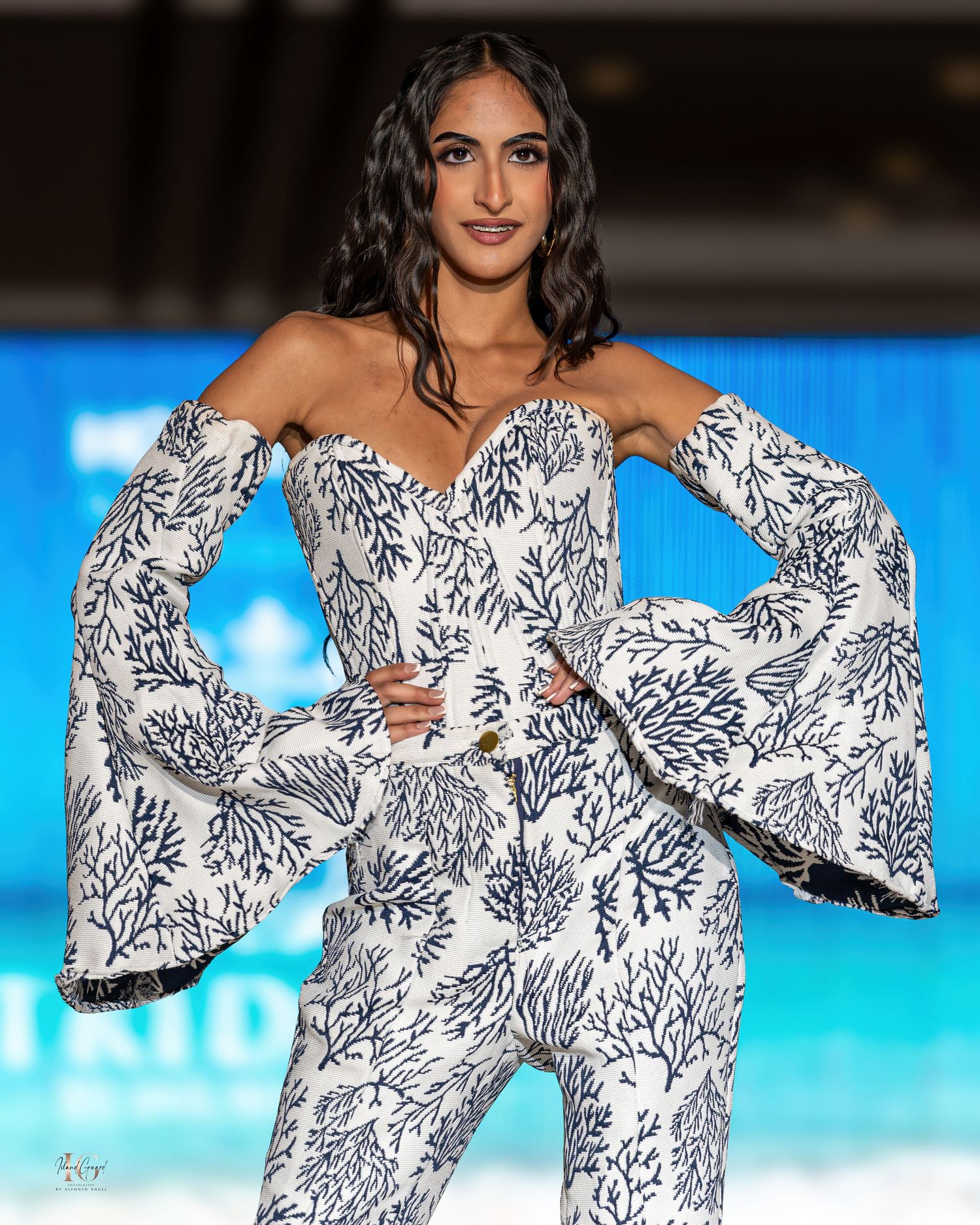Model wearing white and black floral jumpsuit with dramatic bell sleeves on fashion runway.