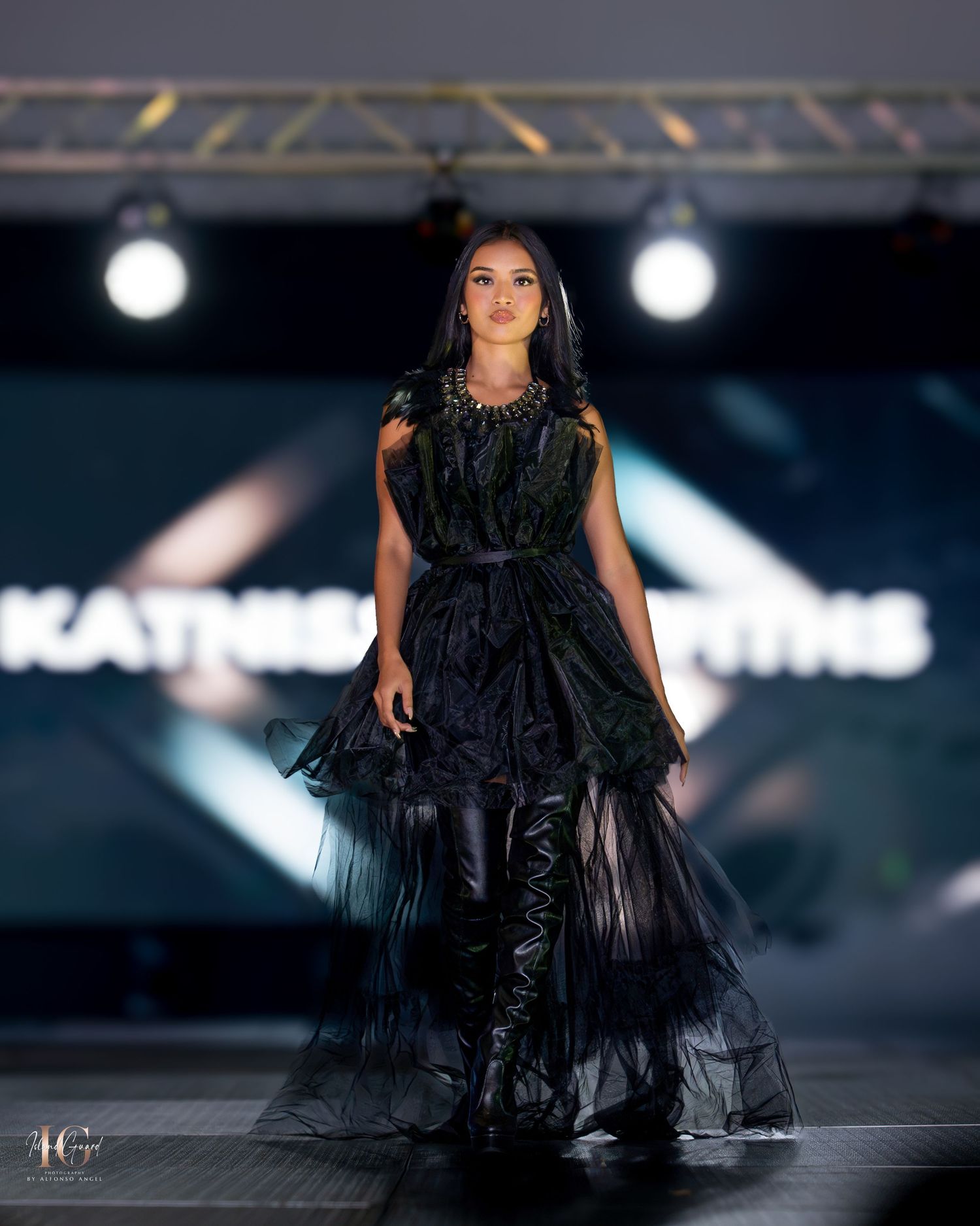 Dramatic black feathered evening gown with voluminous layers showcased at luxury fashion event.