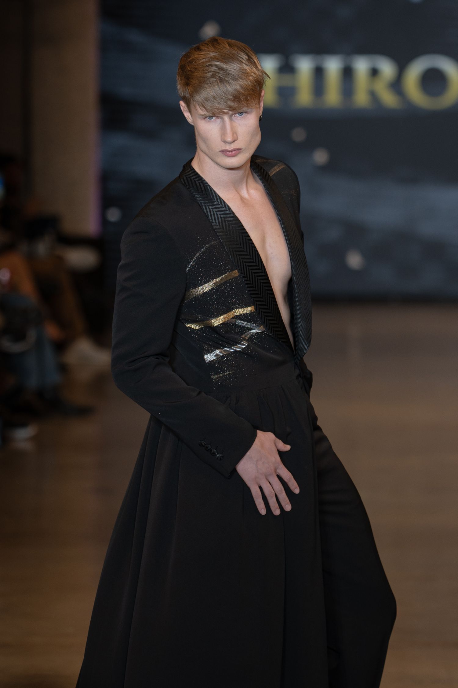 Model walks runway in black avant-garde fashion design with architectural details during fashion show.
