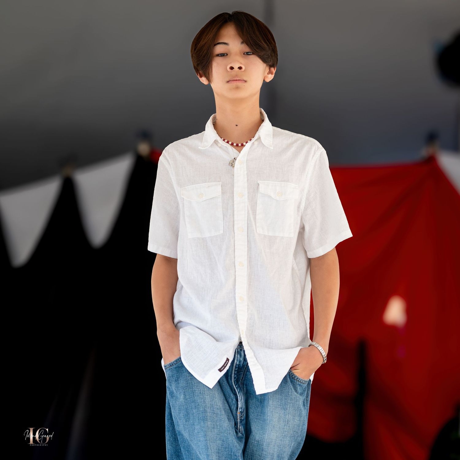 Model in casual white button-up shirt and jeans poses against party decoration background.