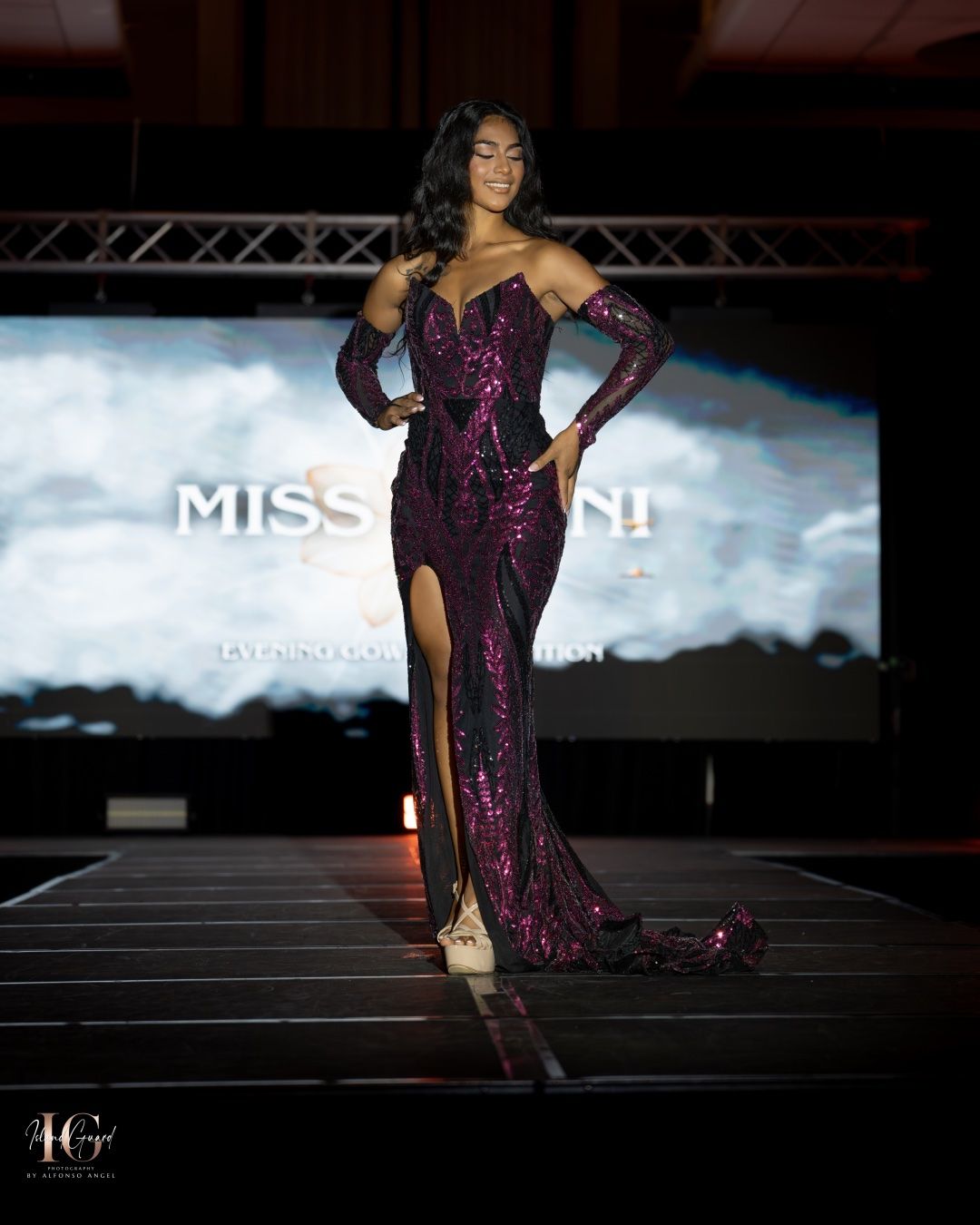 A pageant contestant walks the runway in a stunning purple sequined gown with matching long gloves at a Miss event.
