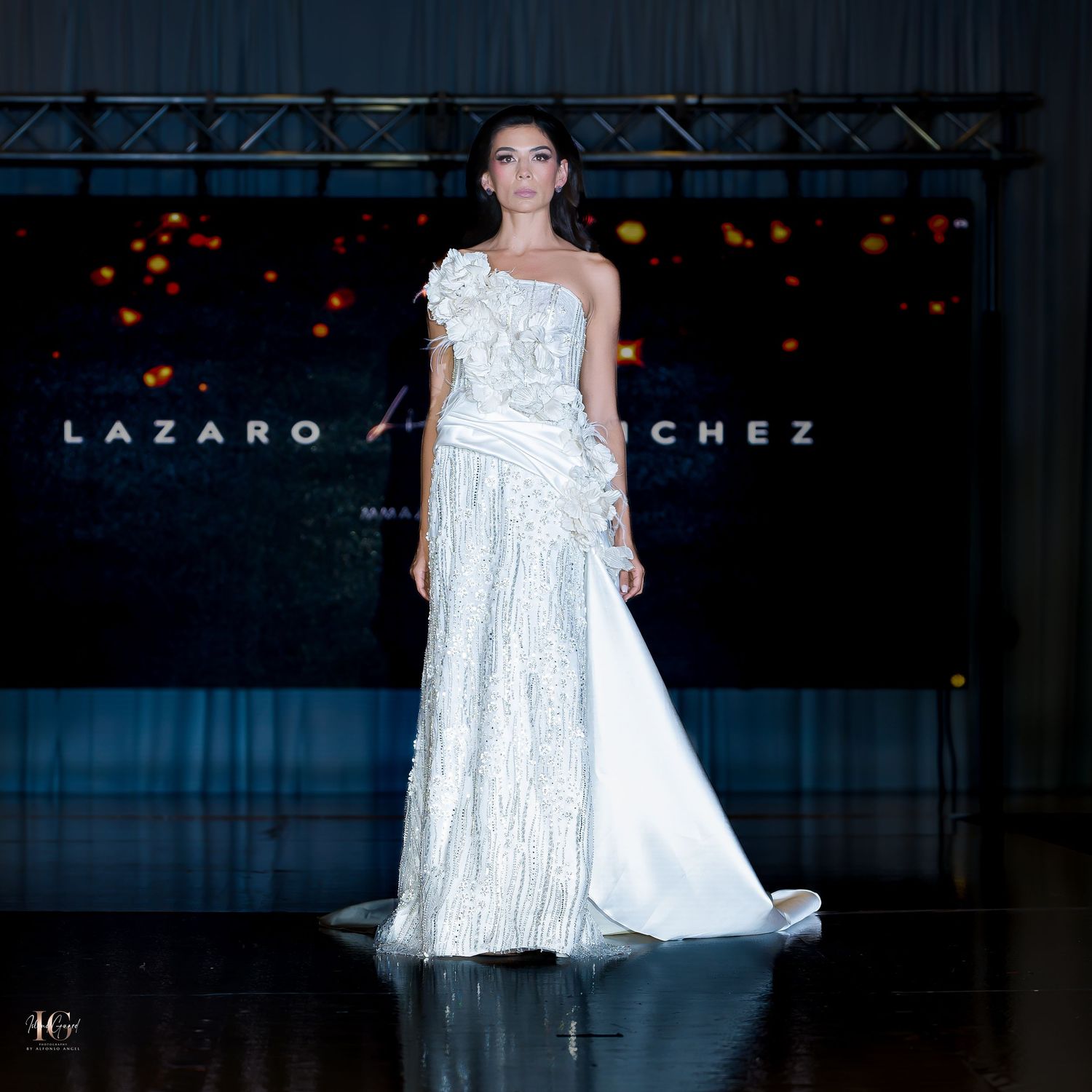 Flowing white bridal gown with layered skirt shown at luxury fashion event.
