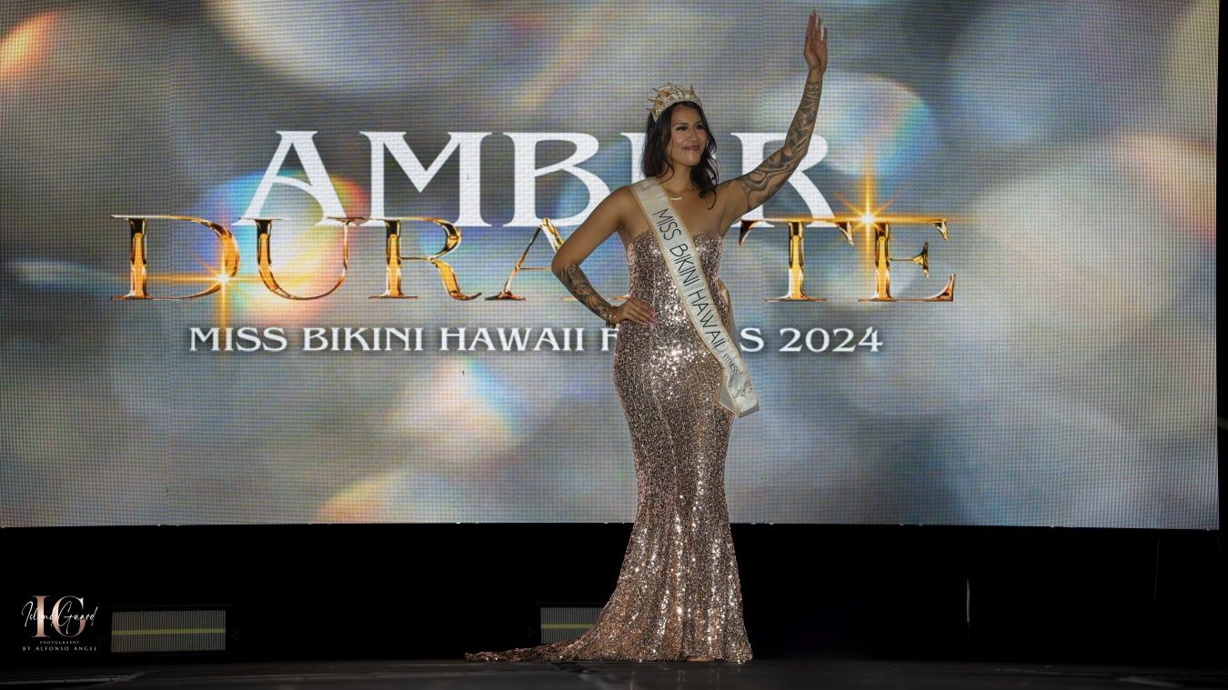 A contestant in a sparkly silver evening gown poses elegantly on stage at the Miss Finland Hawaii pageant 2024.