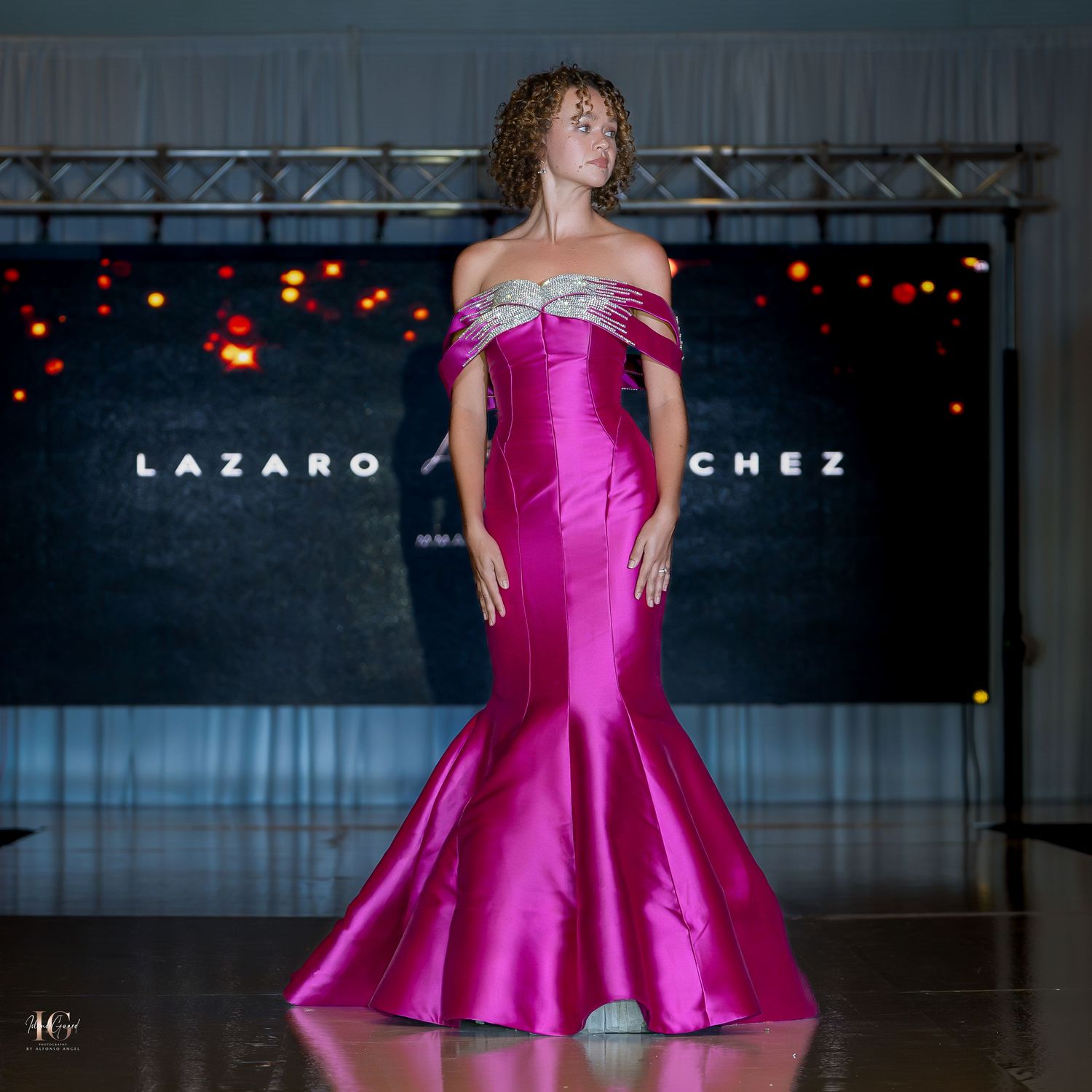 Mermaid-style fuchsia evening gown with off-shoulder design showcased on fashion runway.