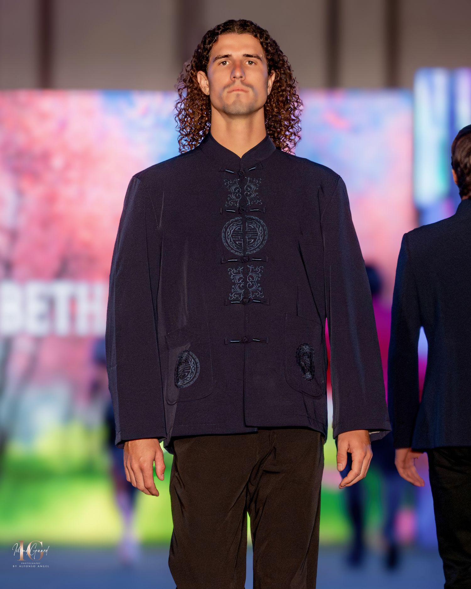 Navy mandarin collar suit jacket showcased during evening fashion presentation.