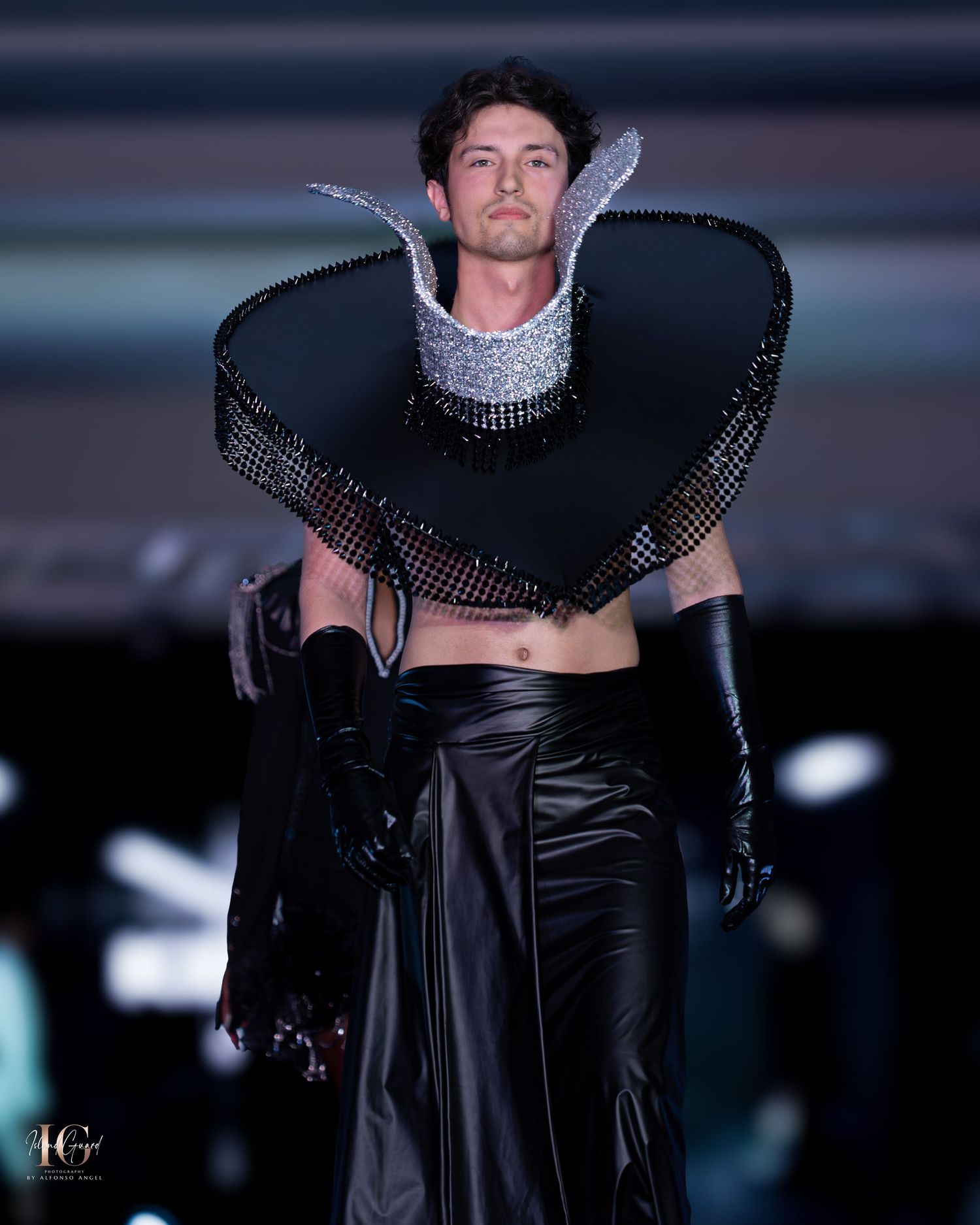Avant-garde black leather ensemble with dramatic collar detail presented on fashion runway.