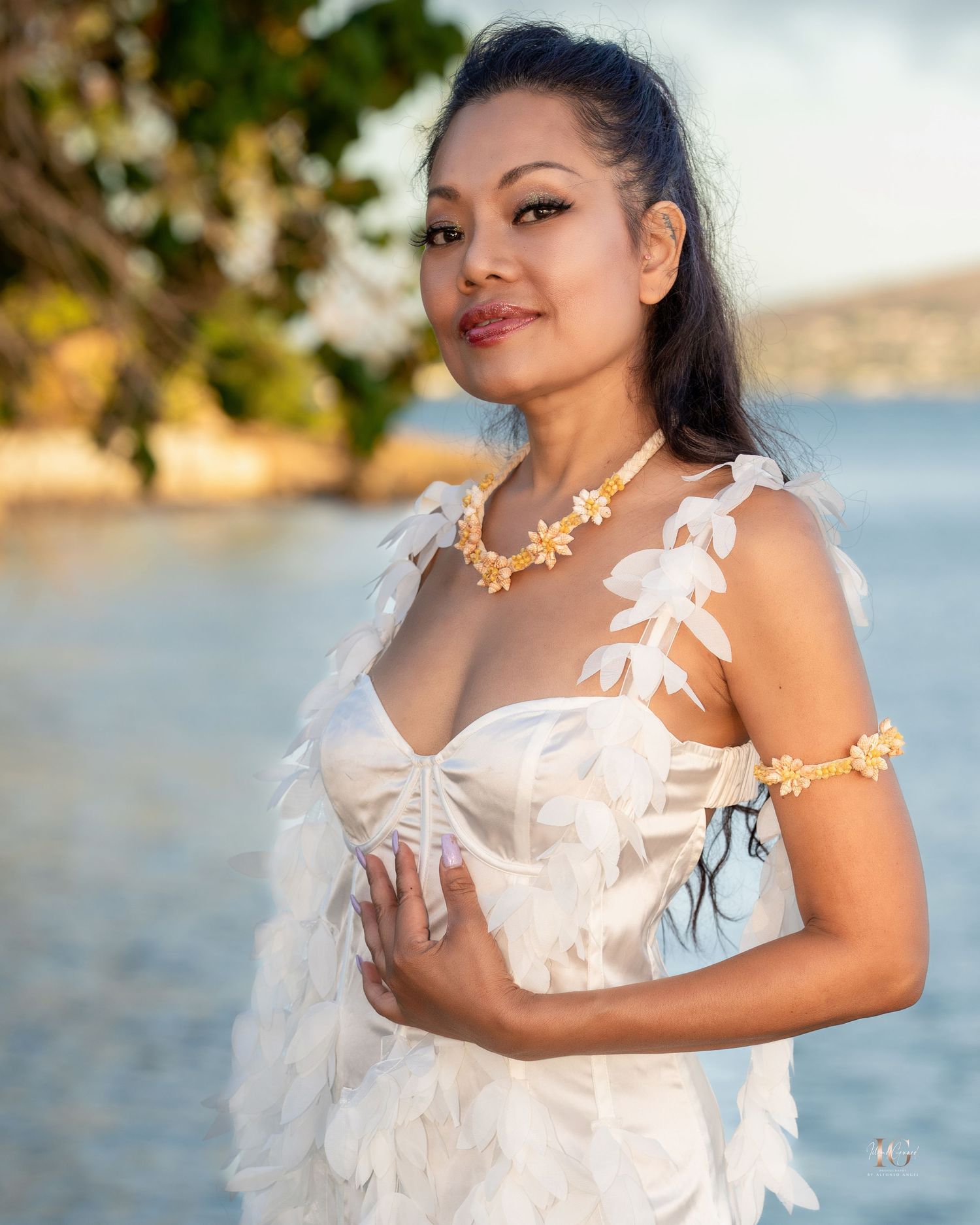 A figure in a white ruffled dress poses gracefully against a waterfront backdrop during a sunset photoshoot.