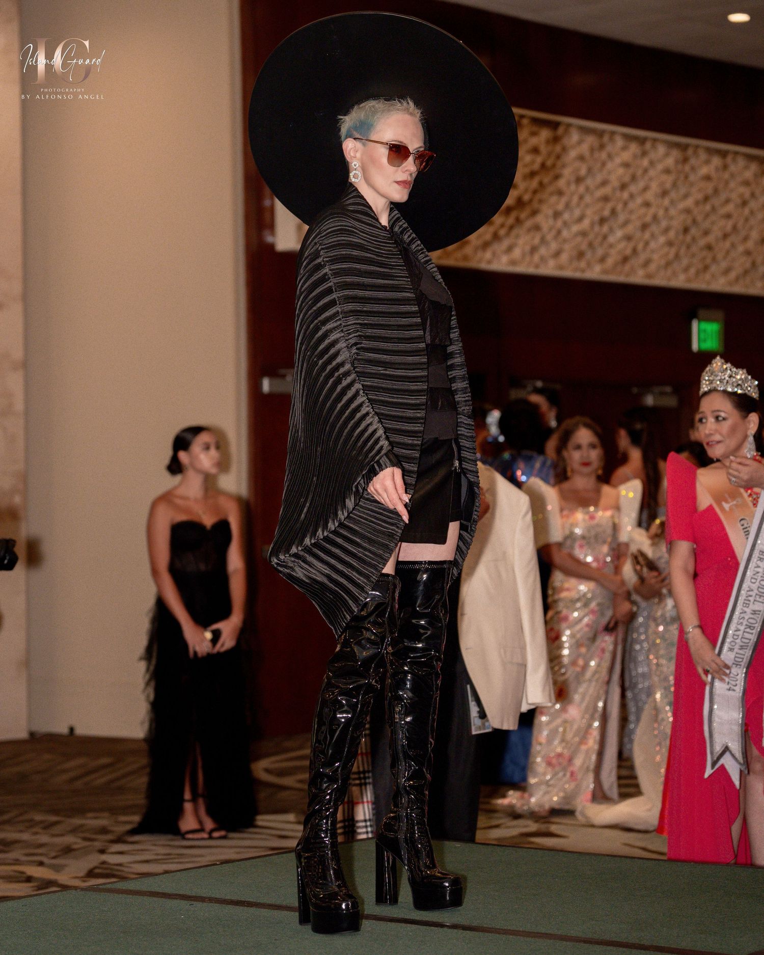 A line of people at a formal event standing along a wall in an indoor venue with carpeted floors.