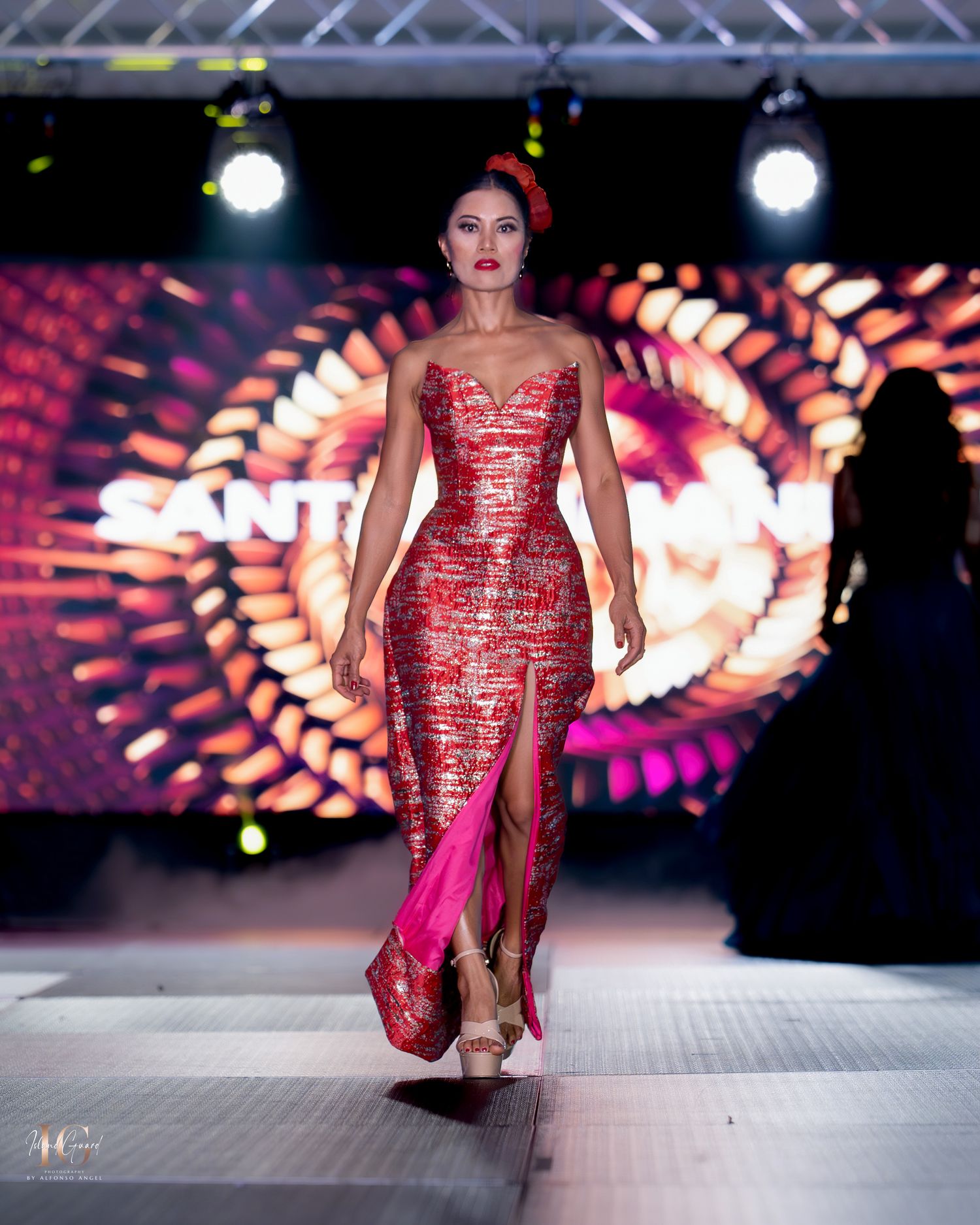 Shimmering red sequin dress glides down runway at upscale fashion show with dramatic lighting.