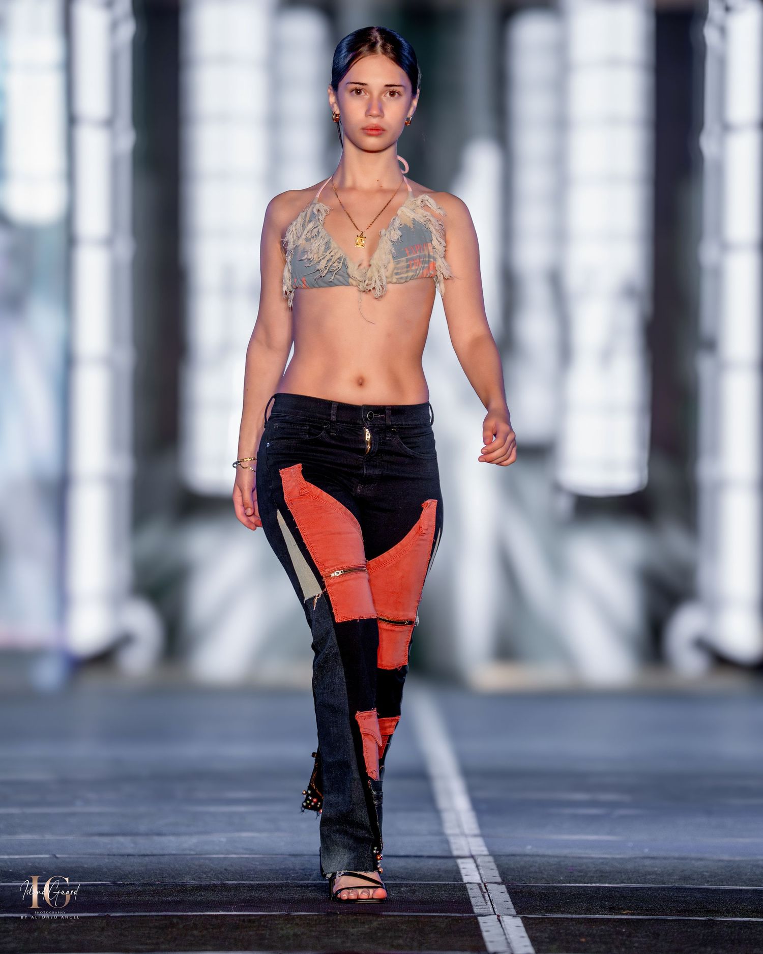 Runway model wearing casual crop top and color-block pants in urban fashion show.